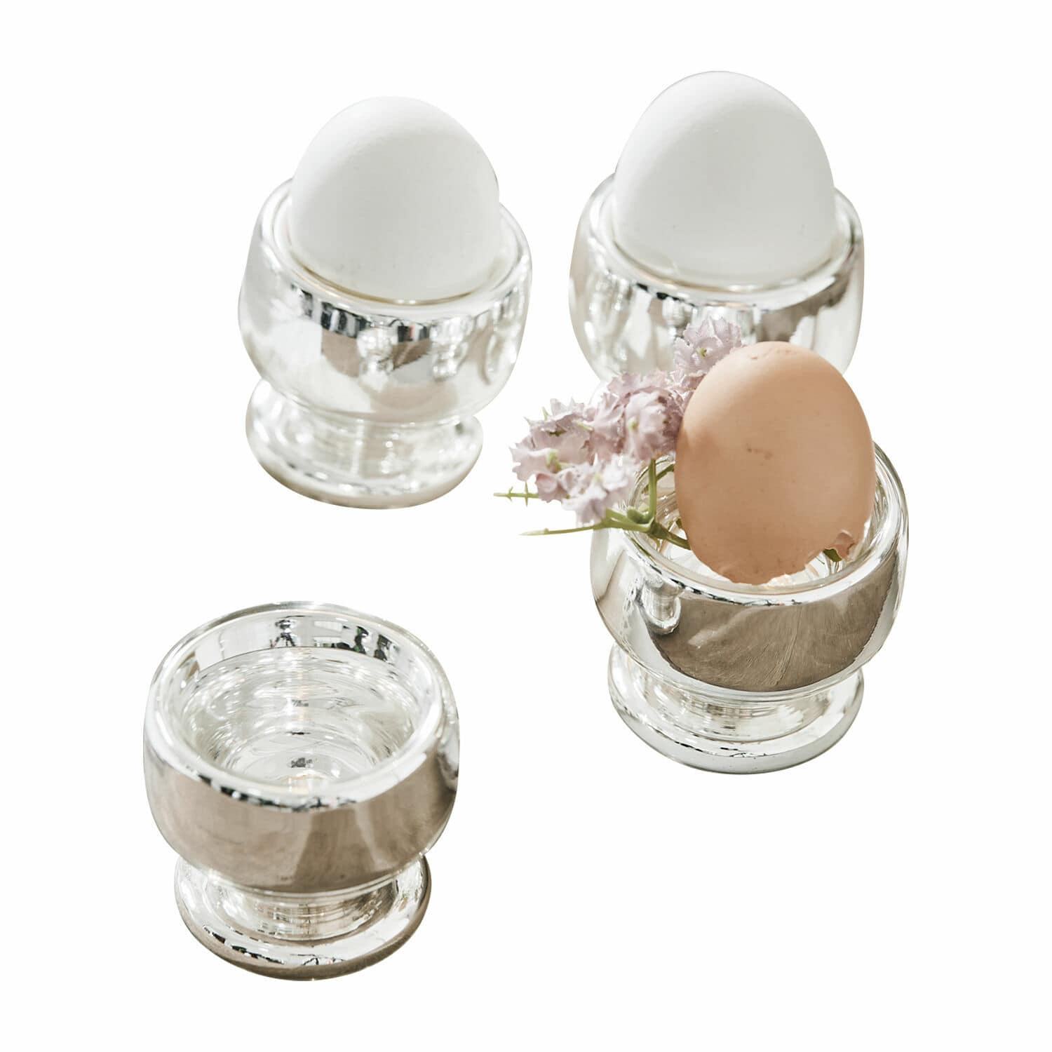 Eierbecher 4er Set Lilligret Vier silberne Metall-Eierbecher mit weißen und braunen Eiern sowie einer kleinen Blume als Dekoration