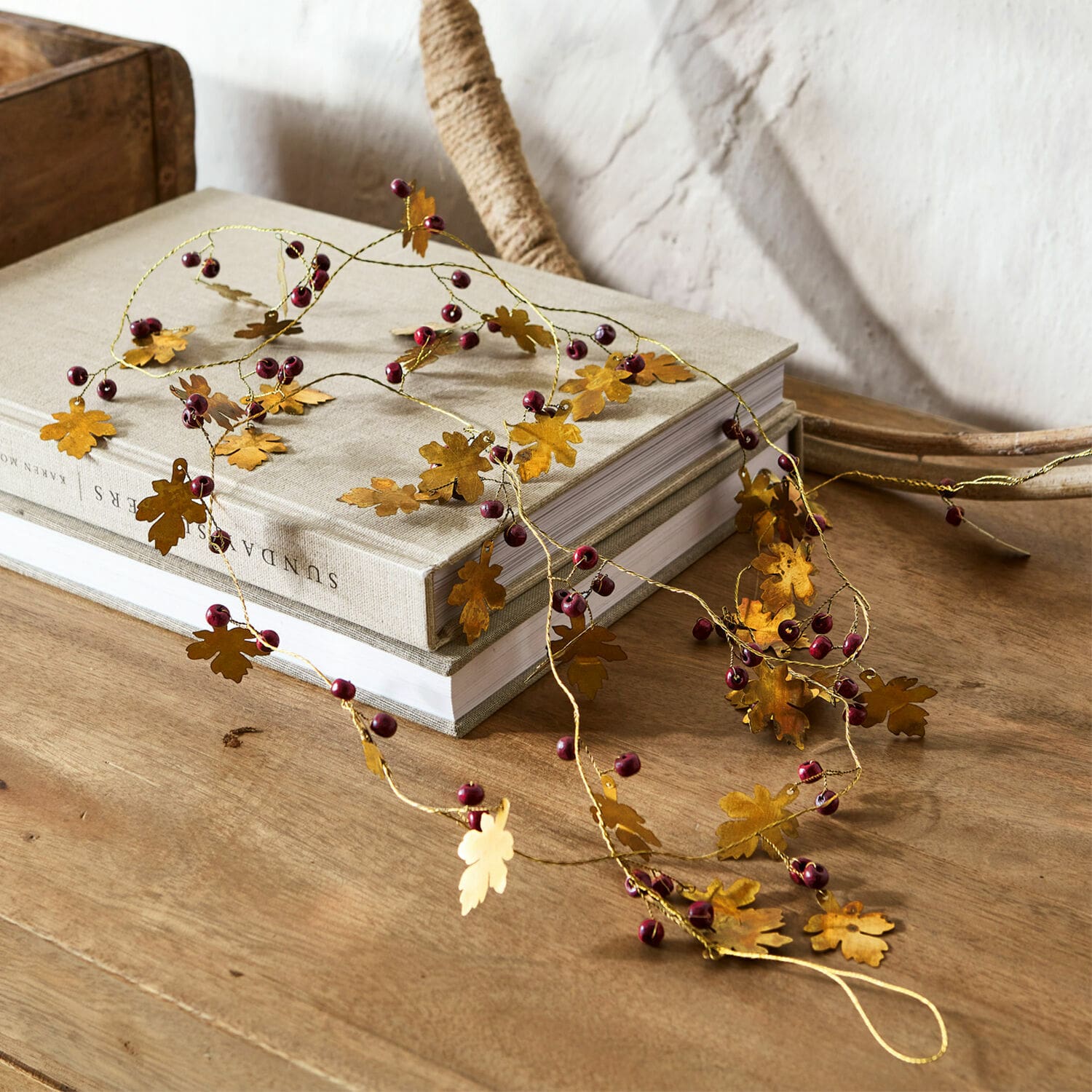 Girlande Liezel Dekorative Girlande mit goldfarbenen Metallblättern und roten Beeren auf Holztisch