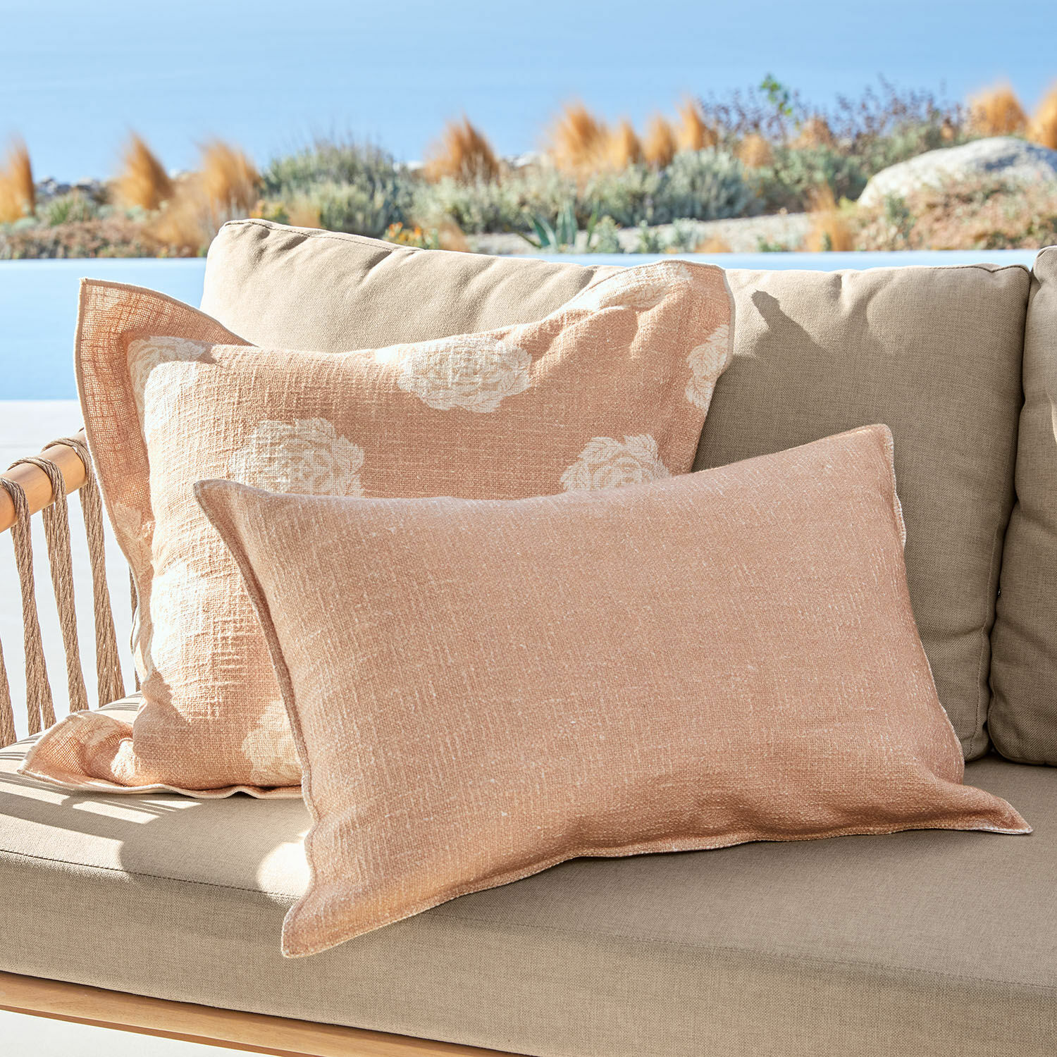 Kissenhülle 2er Set Belvienne Beige Leinen-Dekokissen auf beigem Sofa im Freien mit Blick auf Garten und Himmel