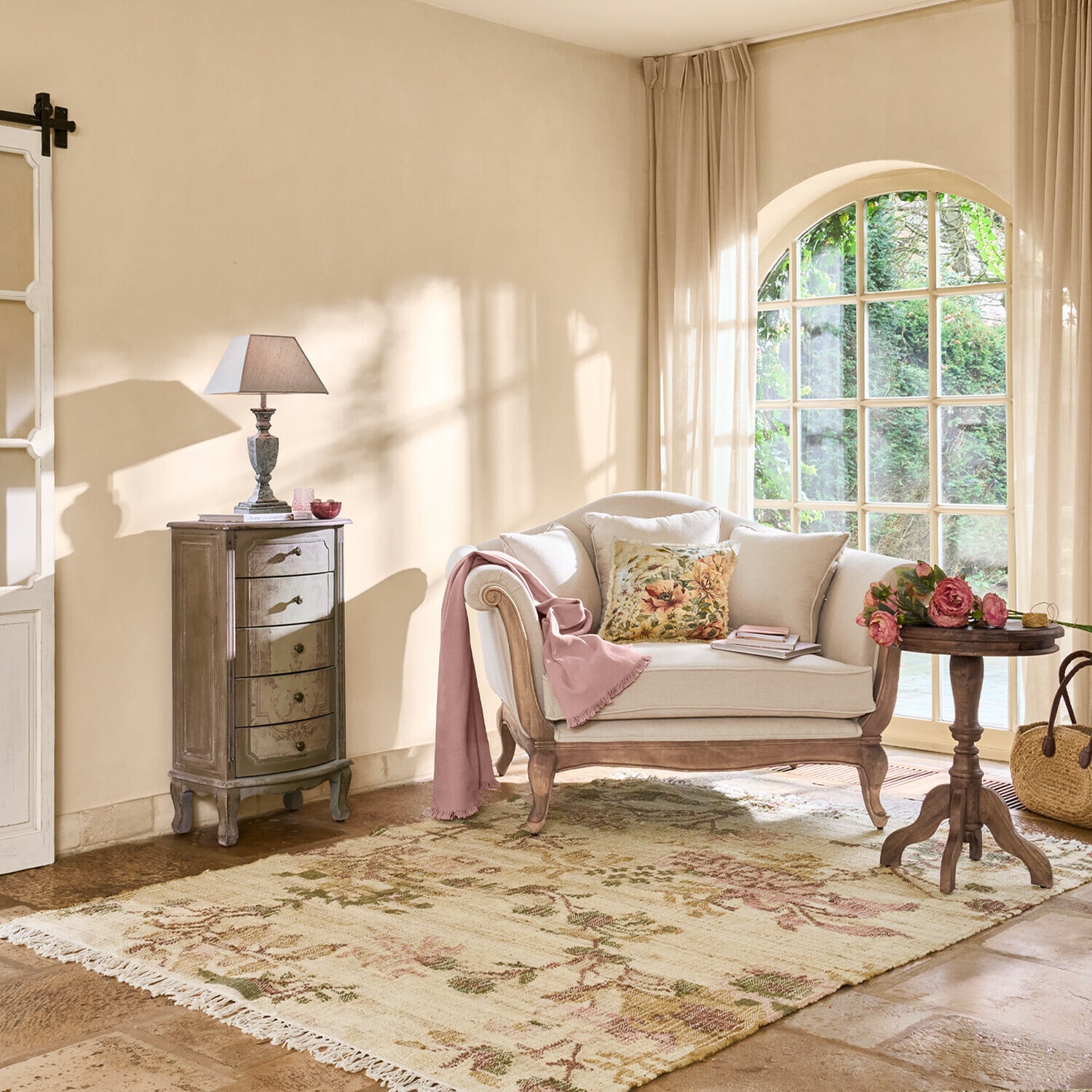 Gemütliches Wohnzimmer mit beigem Holzsofa, floralem Kissen und Blumenmuster-Teppich