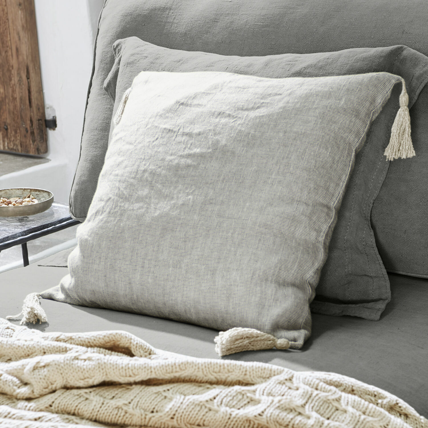 Kissenhülle Loubna Beige Leinen-Dekokissen mit Quasten auf grauem Sofa, gemütliches Wohnaccessoire