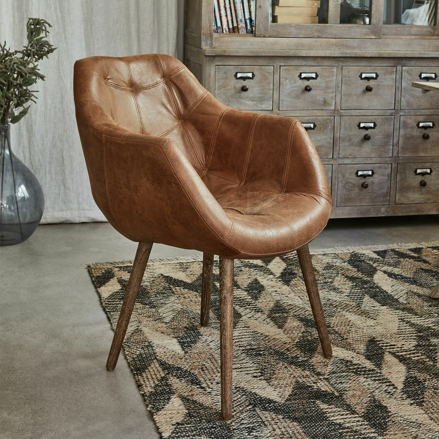 Stuhl Montigny Brauner Sessel aus Kunstleder mit Holzbeinen auf geometrischem Teppich im Wohnzimmer