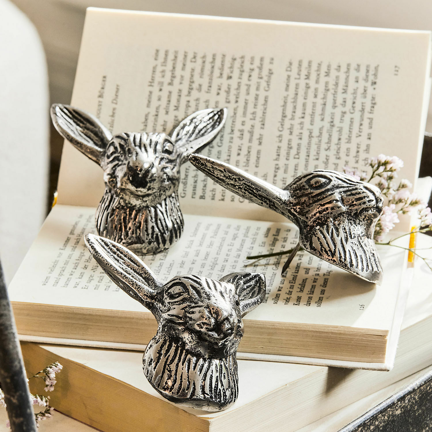Deko-Pin 3er Set Gimont Drei silberne Metall-Dekorationen in Hasenkopf-Form auf offenem Buch, stilvolle Wohnaccessoires