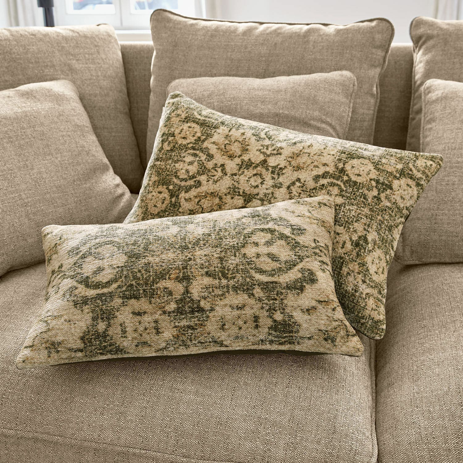 Kissenhülle 2er Set Calperino Zwei dekorative Kissen mit grün-beigem Muster auf beigem Stoff auf Sofa liegend