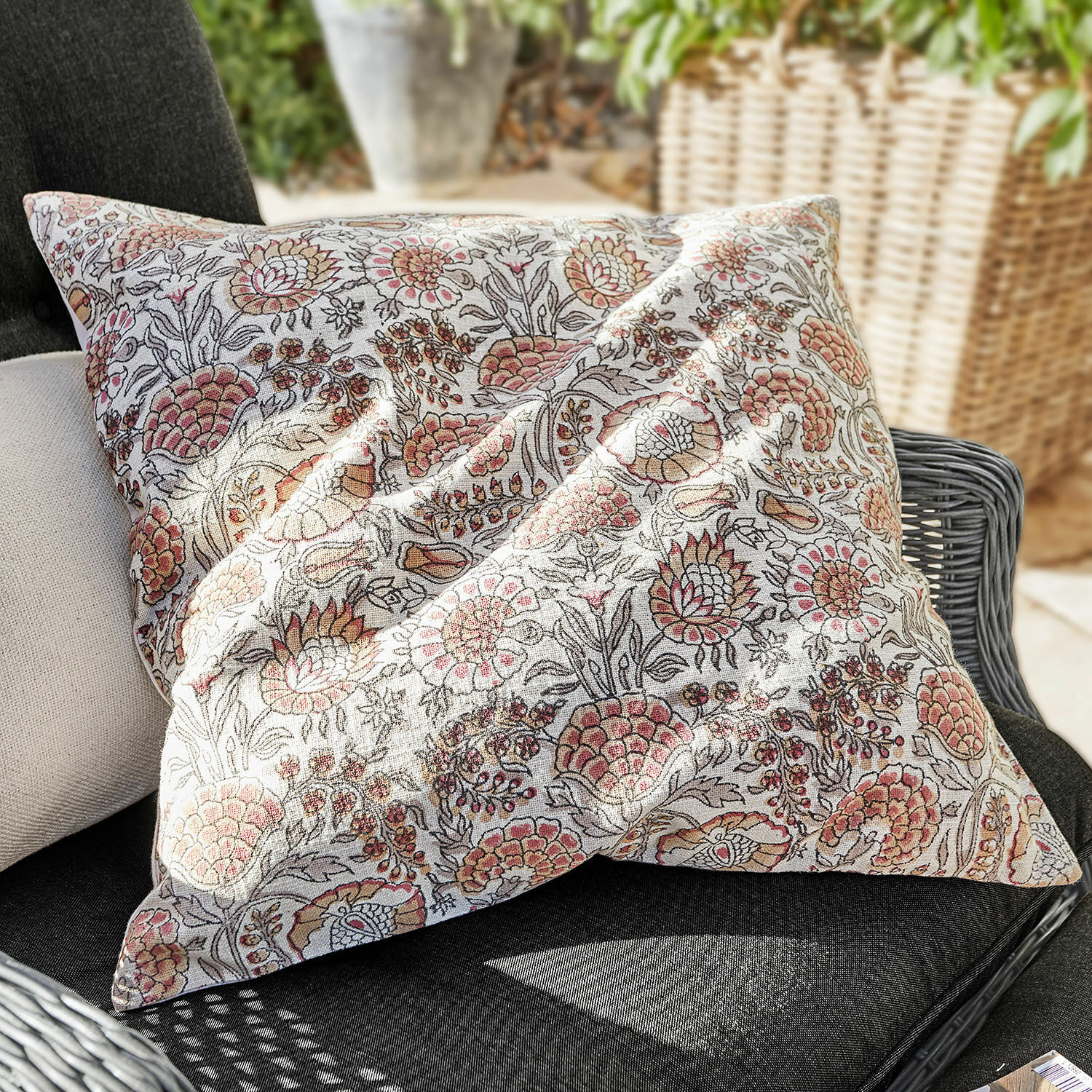 Kissenhülle Romila Dekoratives Baumwollkissen mit floralem Muster in Beige- und Rosatönen auf Gartenstuhl