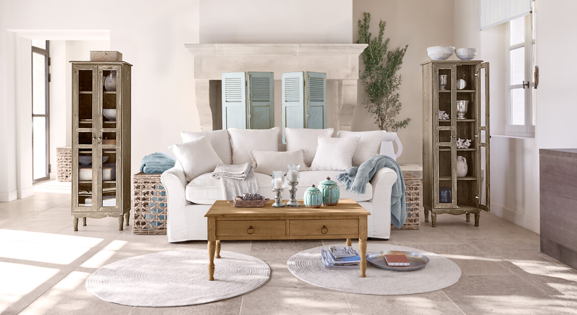 Gemütliches weißes Baumwollsofa im maritimen Stil mit Holztisch und Dekorationen im hellen Wohnzimmer