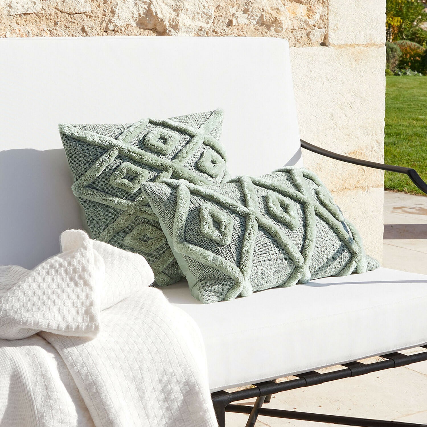 Mintgrüne Dekokissen mit geometrischem Muster auf weißem Sofa mit Decke, Wohntextilien