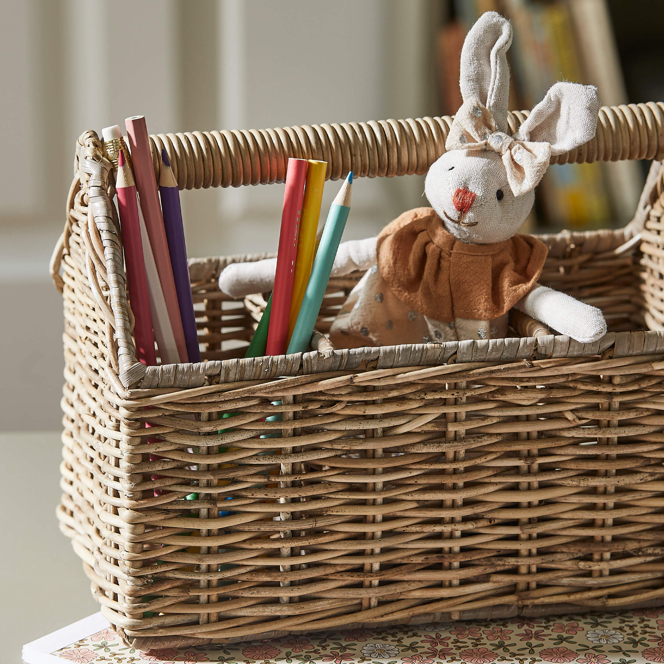 Wiklinerkorb mit bunten Buntstiften und beigem Stoffhasen mit Kleid