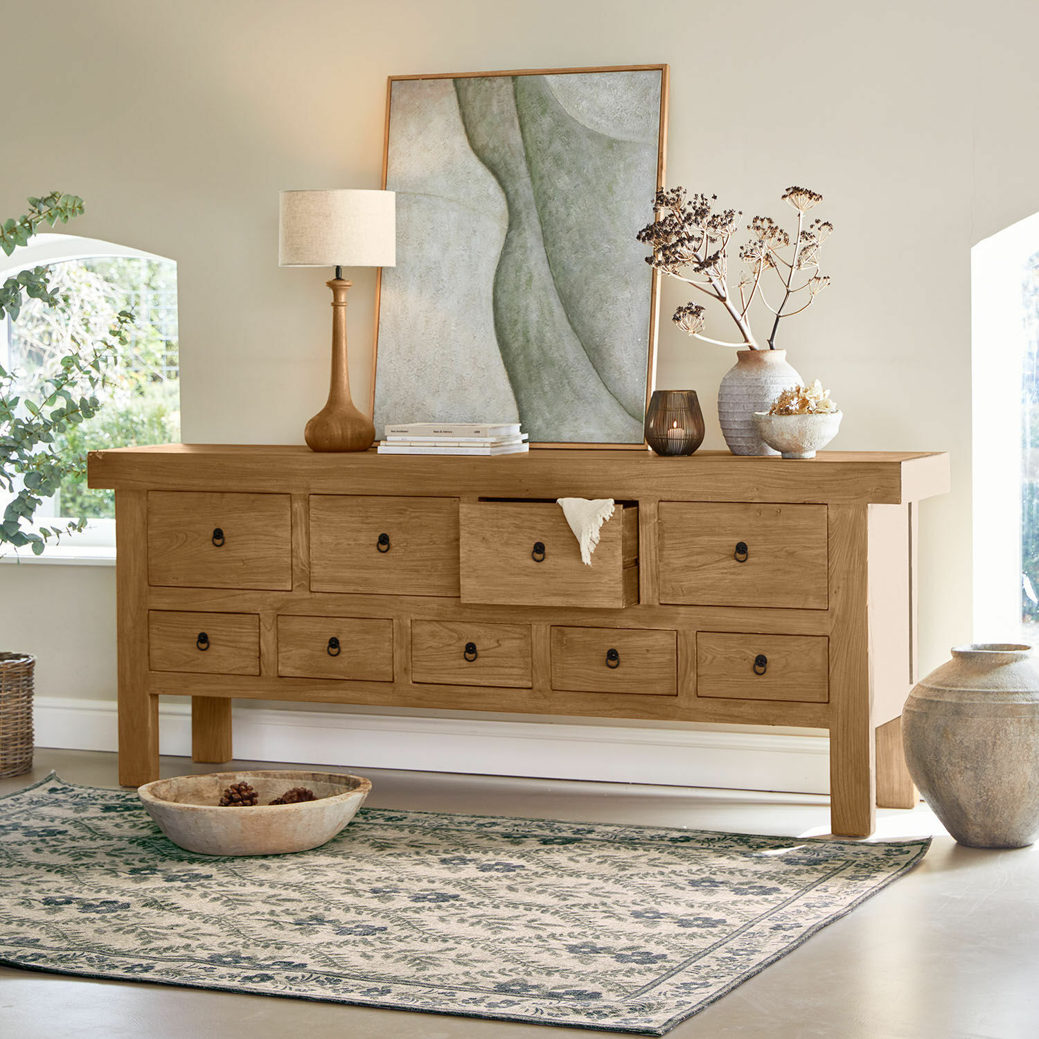 Sideboard Eldonbury Massive Holzkommode in Naturholz mit vielen Schubladen, dekoriert mit Lampe und Vase im hellen Raum