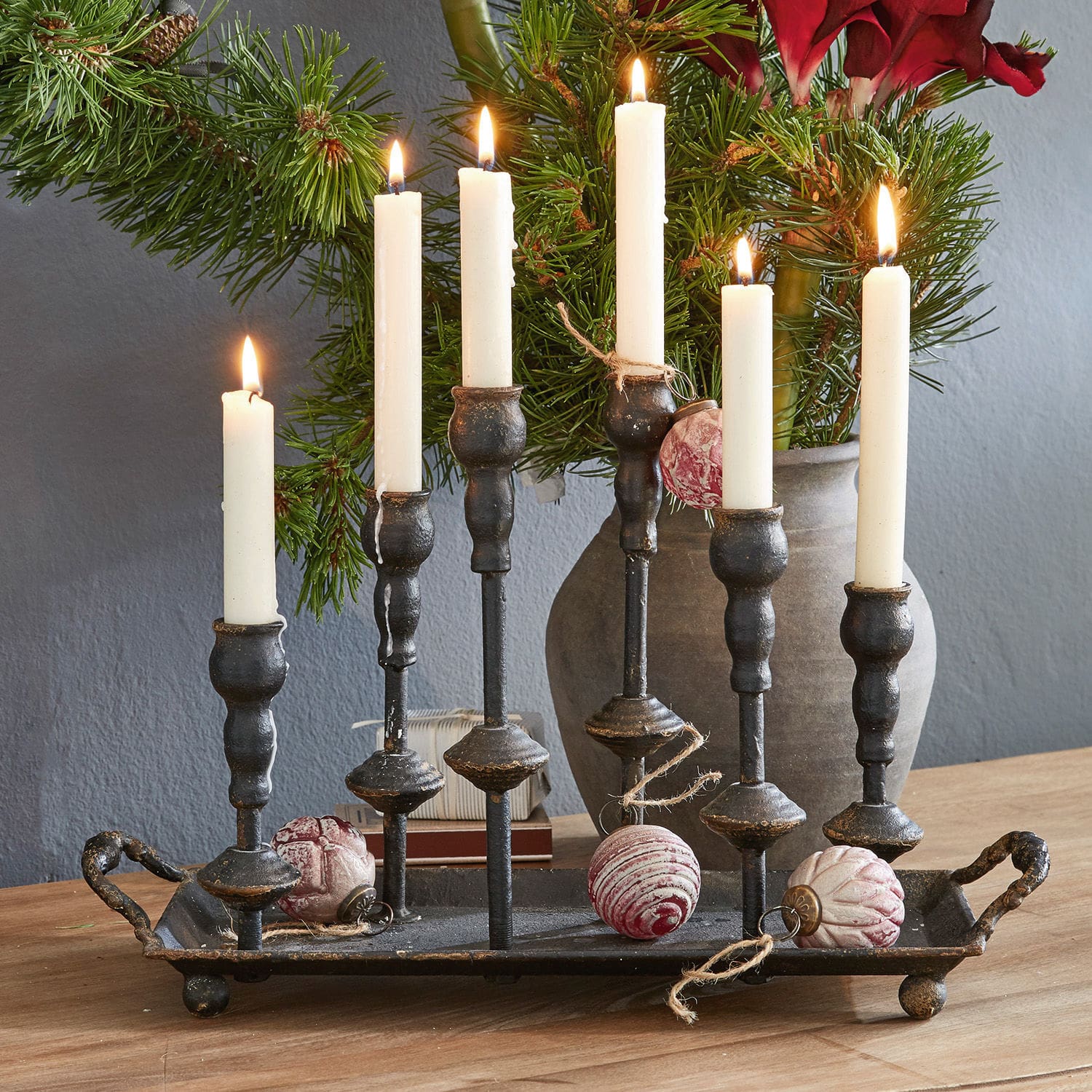 Kerzenständer Aisa Schwarzer Metall-Kerzenhalter mit sechs weißen Kerzen und Weihnachtskugeln auf Holztisch