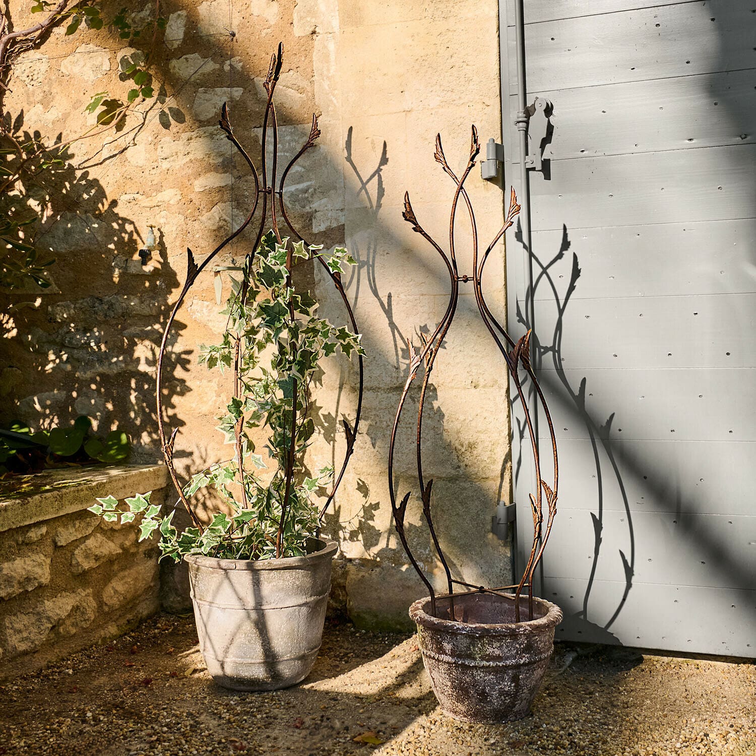 Rankhilfe 2er Set Donnérie Zwei dekorative Metall-Rankhilfen in Steintöpfen auf sonniger Gartenterrasse