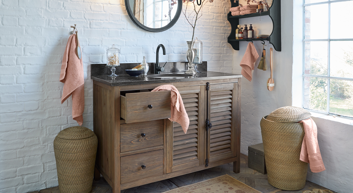 Badezimmer mit Holzschrank, schwarzer Arbeitsplatte und terrakottafarbenen Handtüchern, natürliche Deko