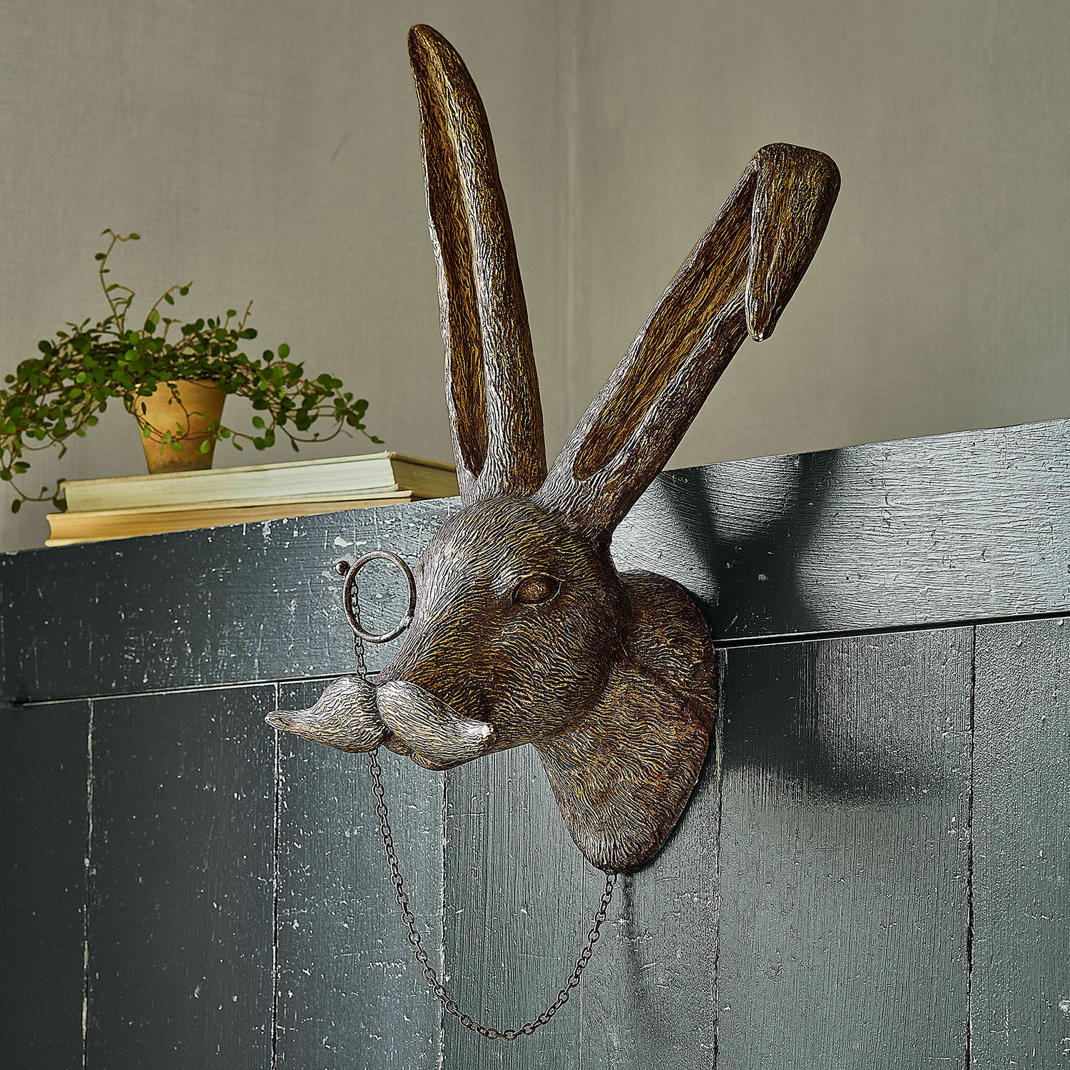 Dekorativer brauner Metall-Hasenkopf mit Schnurrbart und Monokel an der Wand