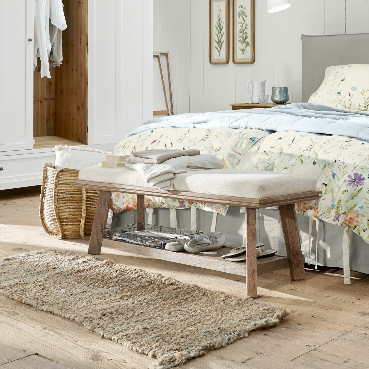 Bank Abington Holzbank mit hell gepolstertem Sitz im Schlafzimmer, natürlicher Teppich und florale Dekoration