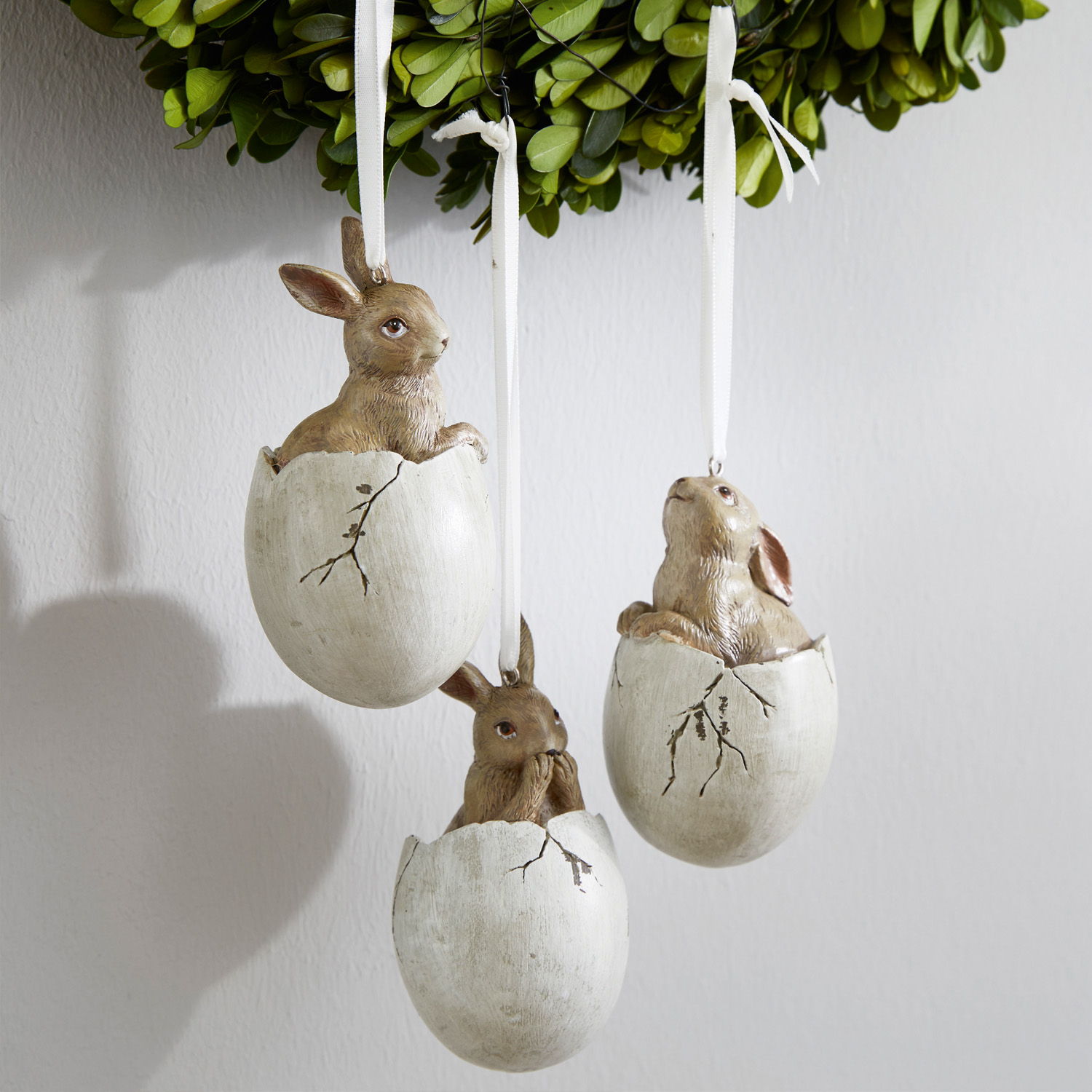 Drei hängende Osterdekorationen mit Hasen in weißen Eierschalen aus Kunstmaterial
