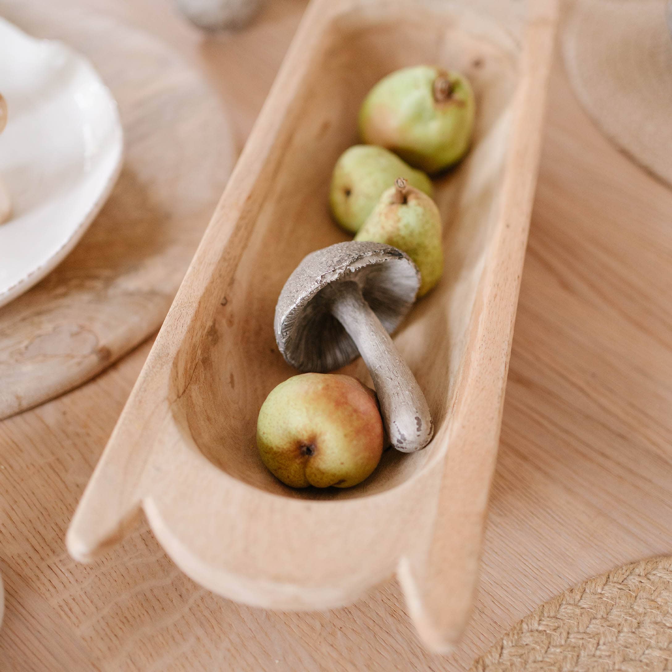 Holzschale mit dekorativem Pilz und grünen Birnen als herbstliche Tischdeko