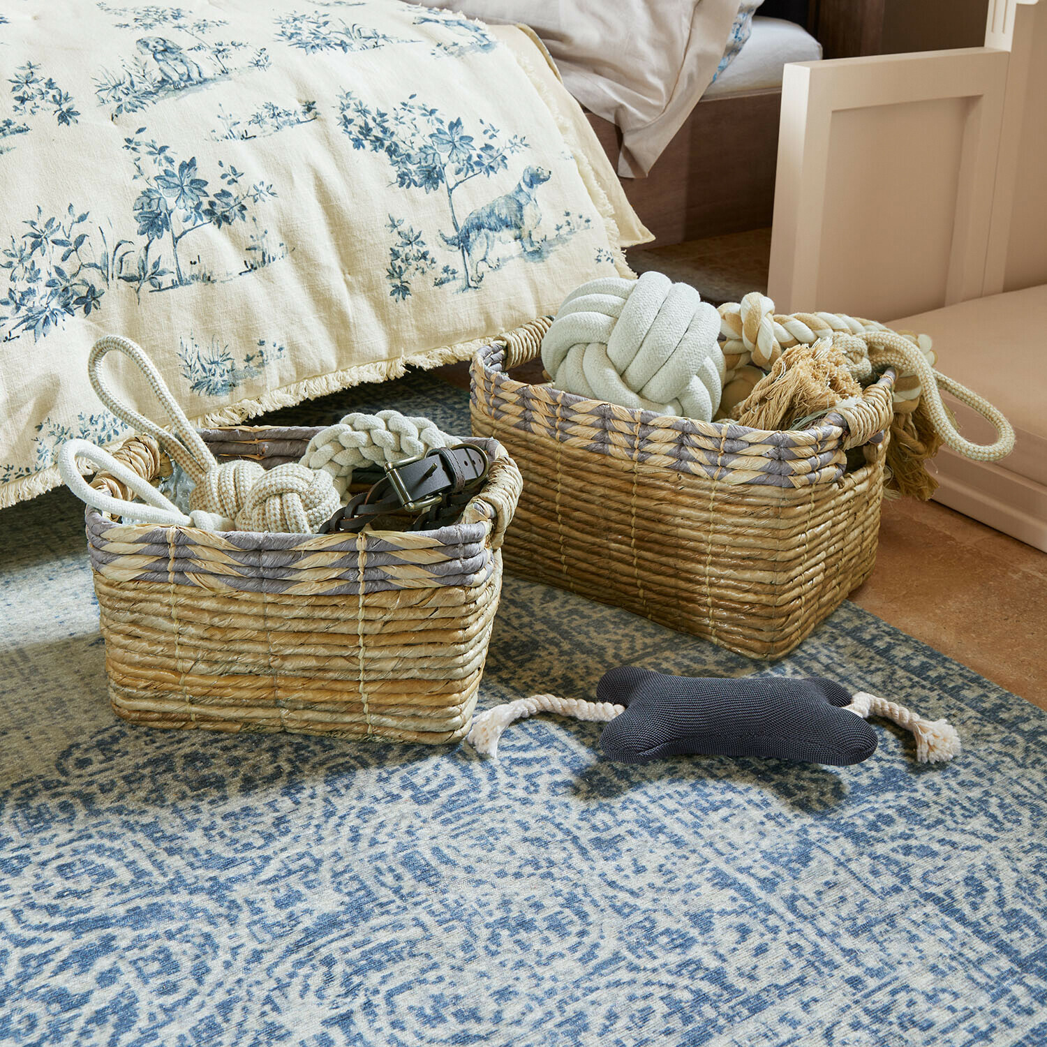 Korb 2er Set Kalimonde Zwei natürliche Korbwarenkörbe mit Hundespielzeug auf blauem Teppich im Schlafzimmer