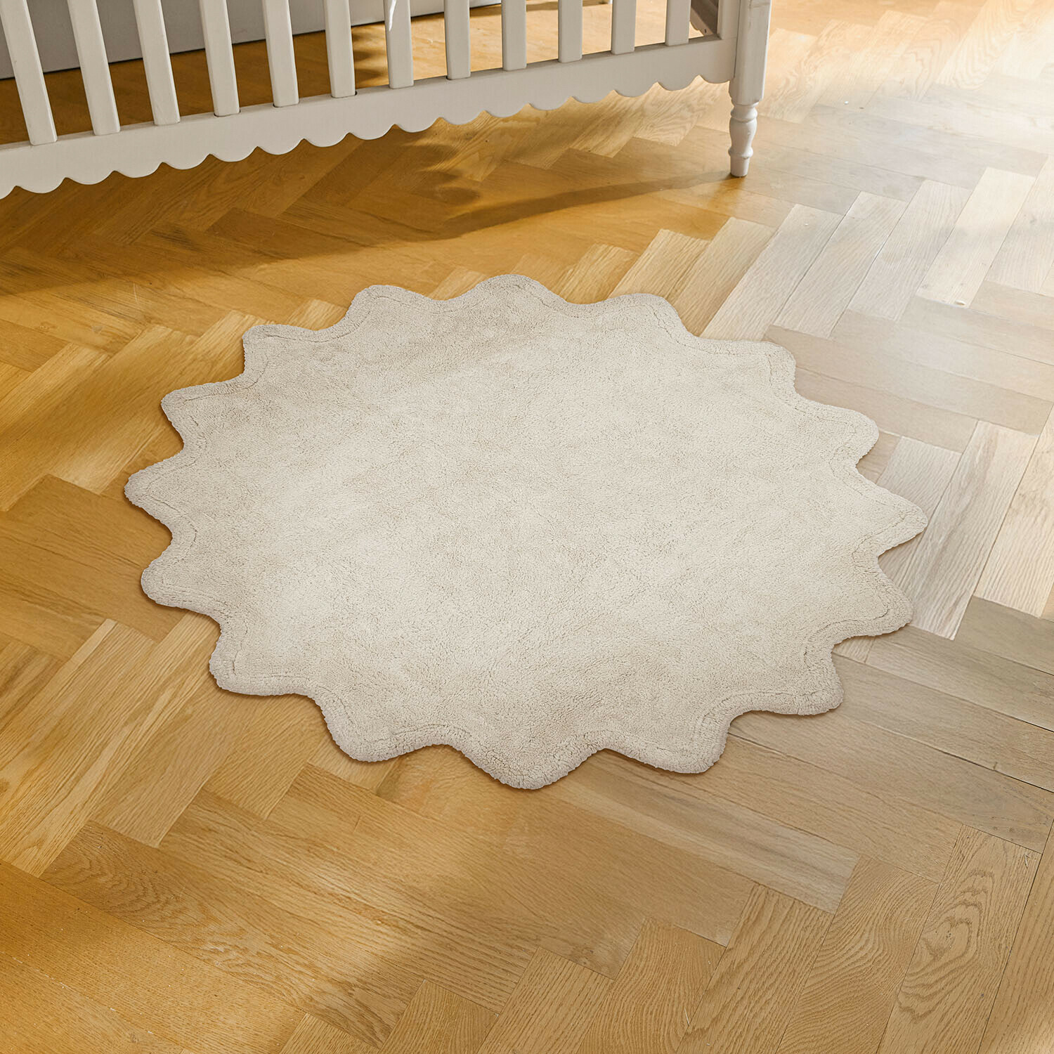 Runder Teppich aus weichem beigem Material mit wellenförmigem Rand auf hellem Holzboden