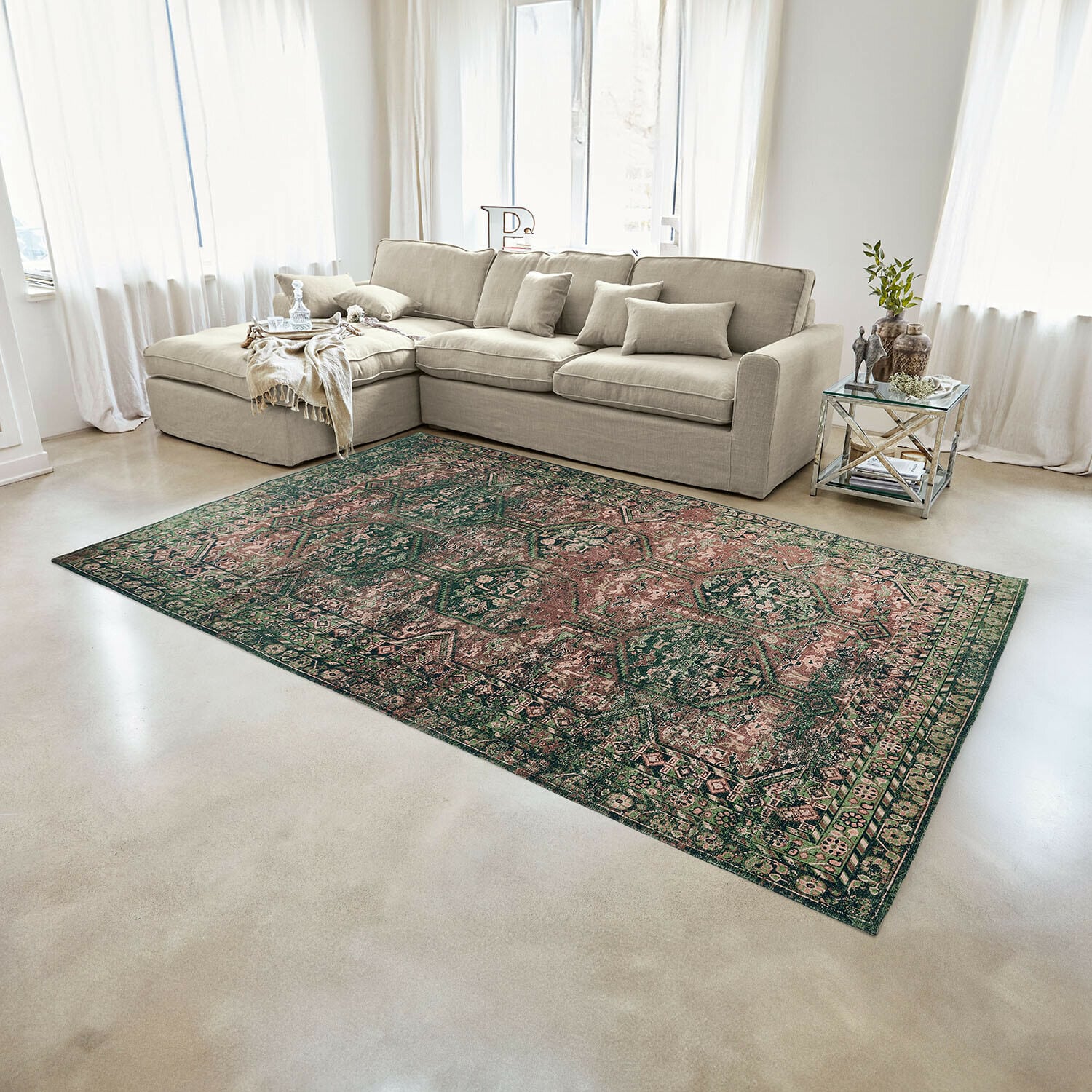 Teppich Incantaro Grün-rosa gemusterter Teppich auf hellem Boden in modernem Wohnzimmer mit beigem Sofa