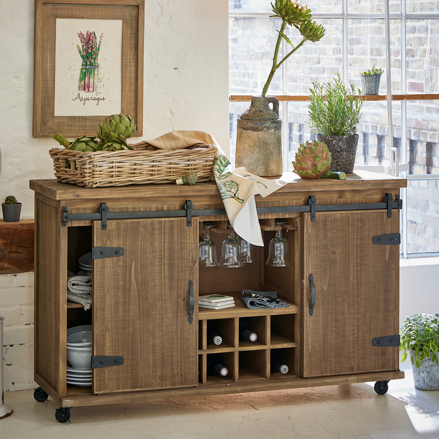 Kommode Grasse Holzkommode auf Rollen mit Weinregal und Gläserhalter, dekoriert mit grünen Pflanzen und Gemüsekorb