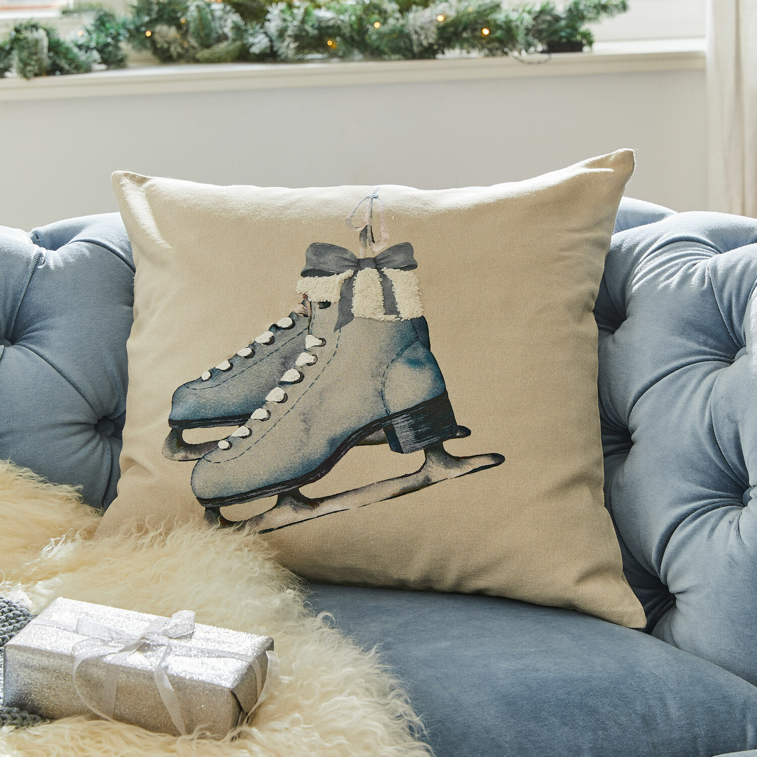 Kissenhülle Herveline Beiges Kissen mit blauem Schlittschuh-Motiv auf blauem Sofa, winterliche und festliche Dekoration
