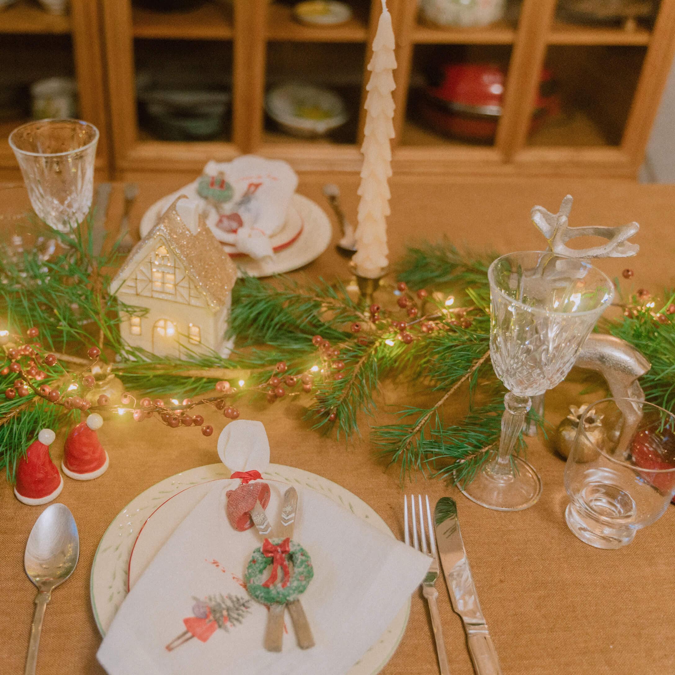 Weihnachtlich gedeckter Tisch mit grünen Zweigen, Kerzen und Kristallgläsern für festliche Stimmung