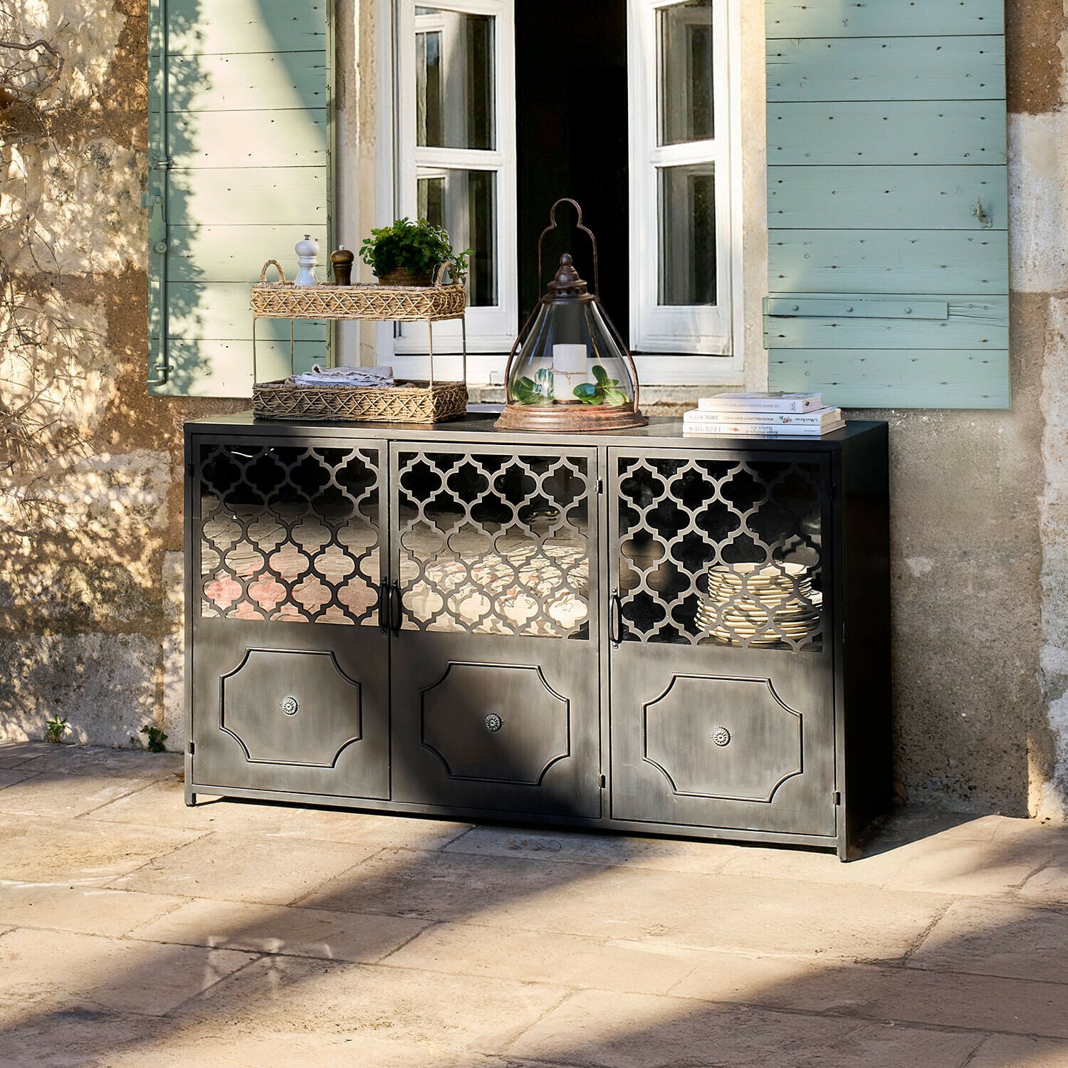 Sideboard Astralon Schwarzer Metall-Sideboard mit filigranen Türen auf Terrasse vor Fenster mit grünen Fensterläden