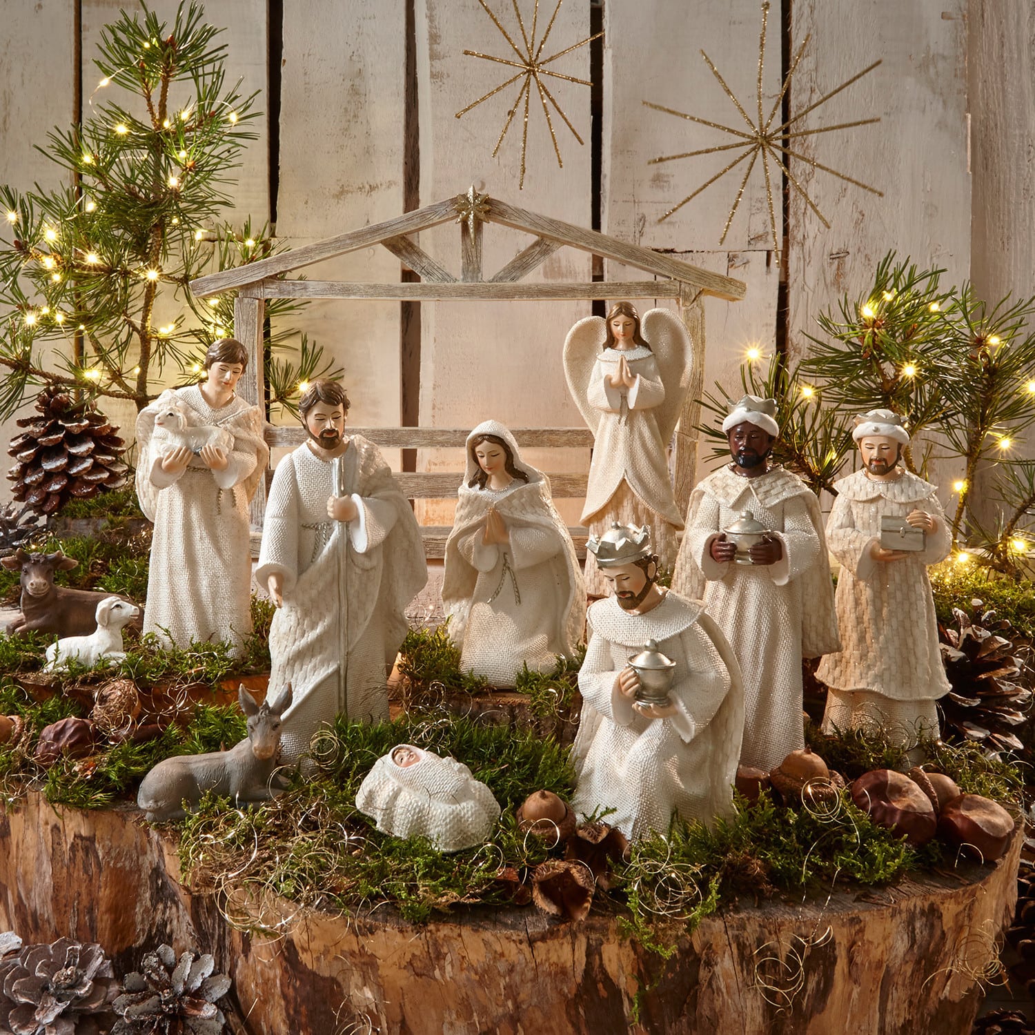 Krippenfiguren 12er Set Santo Weißes Krippenfiguren-Set aus Holz und Stoff auf natürlichem Moos- und Lichterhintergrund zur Weihnachtsdekoration