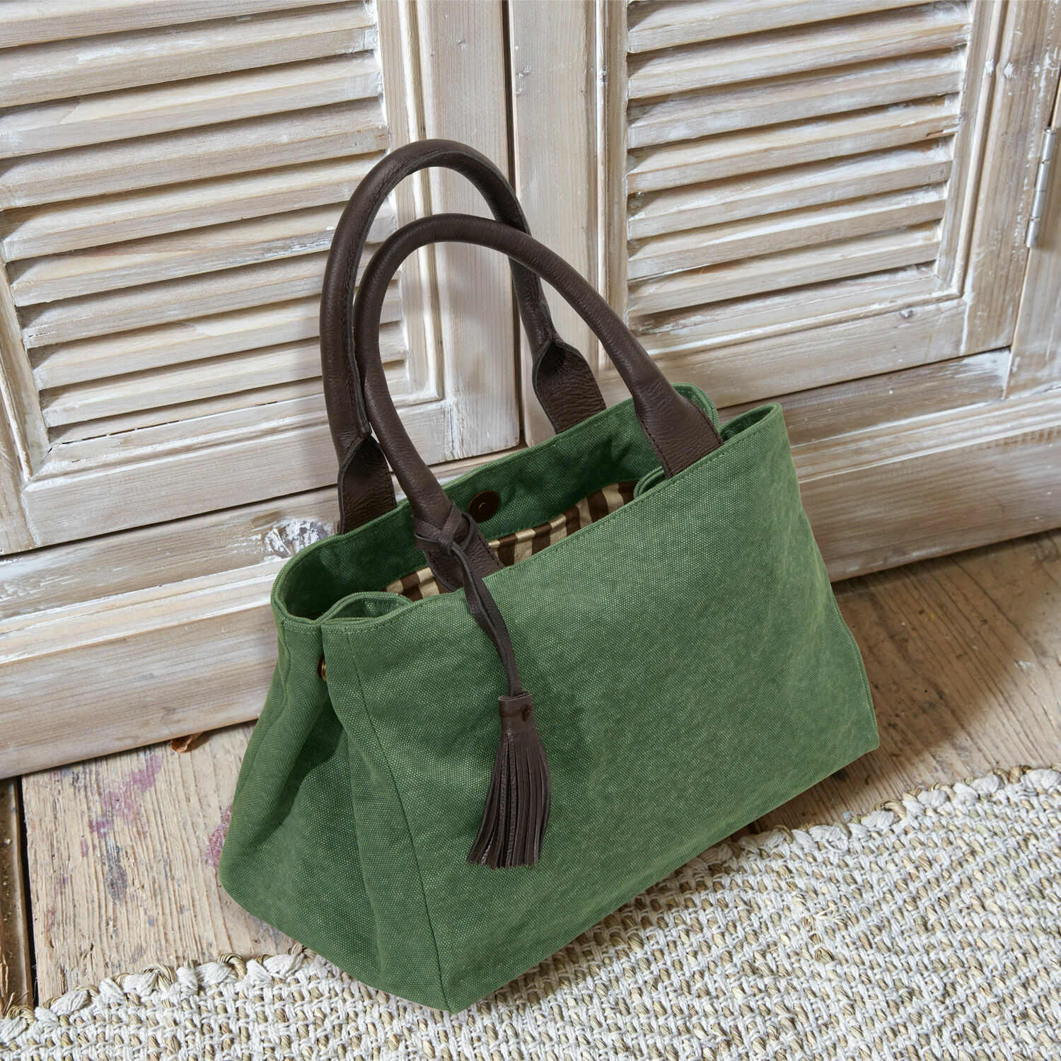 Tasche Hoya Grüne Stofftasche mit braunen Ledergriffen und Quaste auf hellem Holzboden