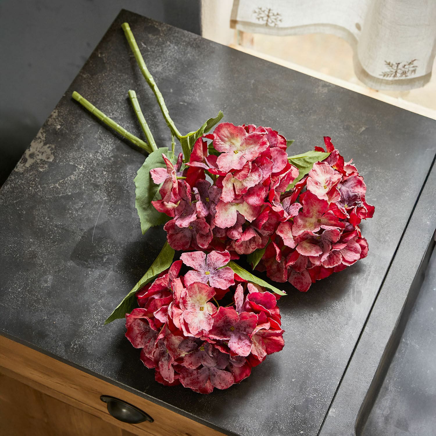 Deko-Blume 3er Set Virette Kunsthortensien-Bündel in rot-rosa Tönen mit grünen Blättern auf dunkler Oberfläche