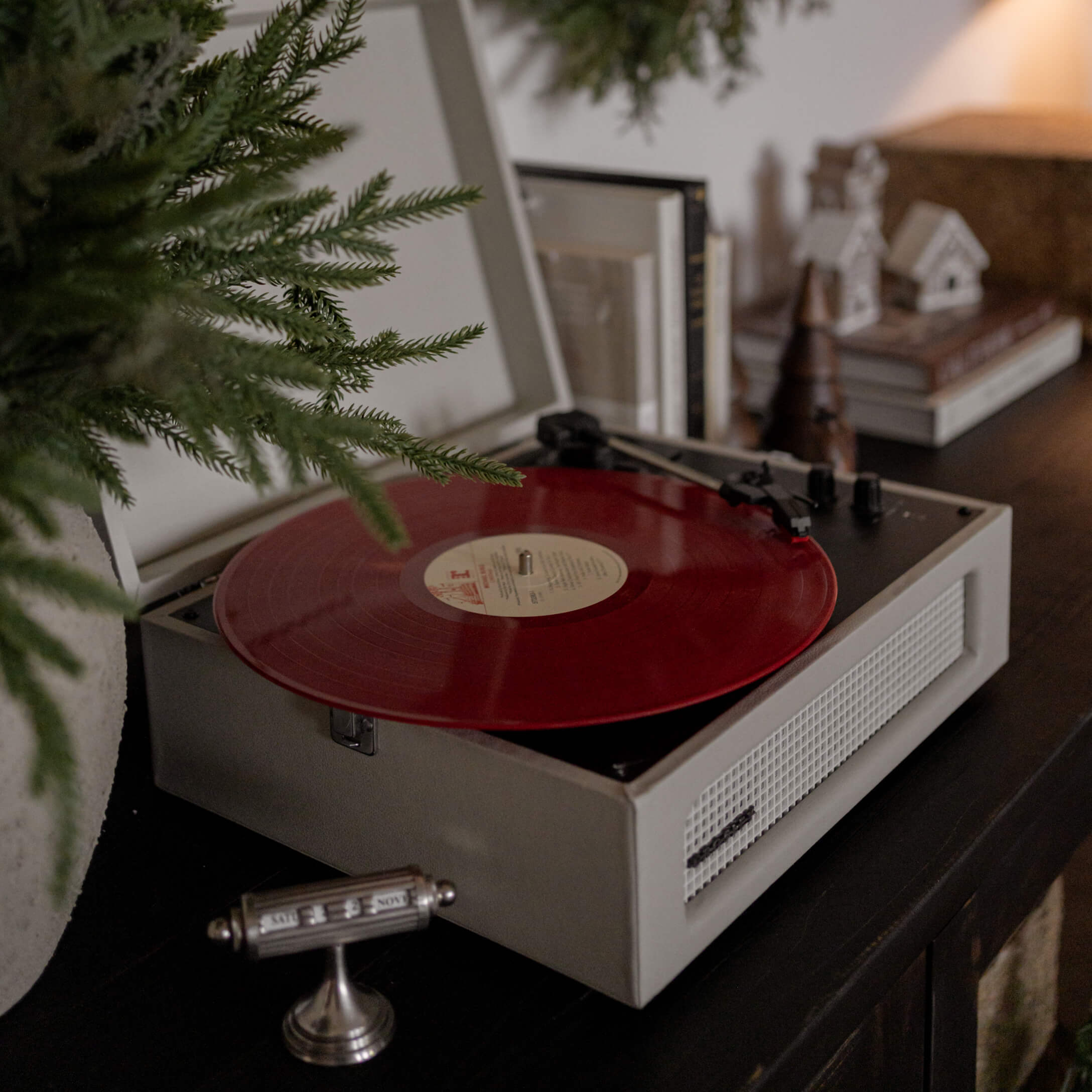 Retro-Plattenspieler mit roter Vinyl-Schallplatte auf dunklem Möbel in gemütlichem Raum