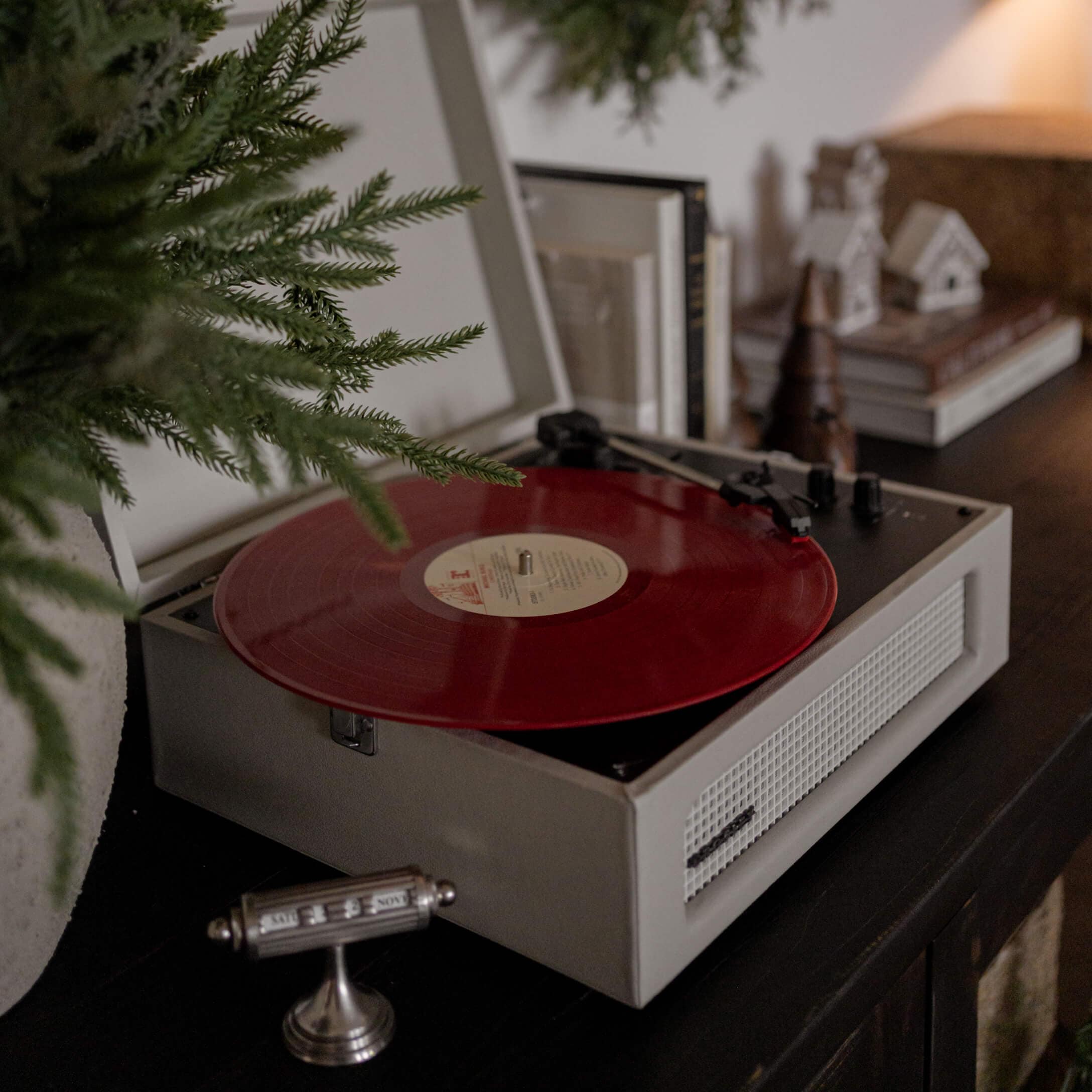 Retro-Plattenspieler mit roter Vinyl-Schallplatte auf dunklem Möbel in gemütlichem Raum