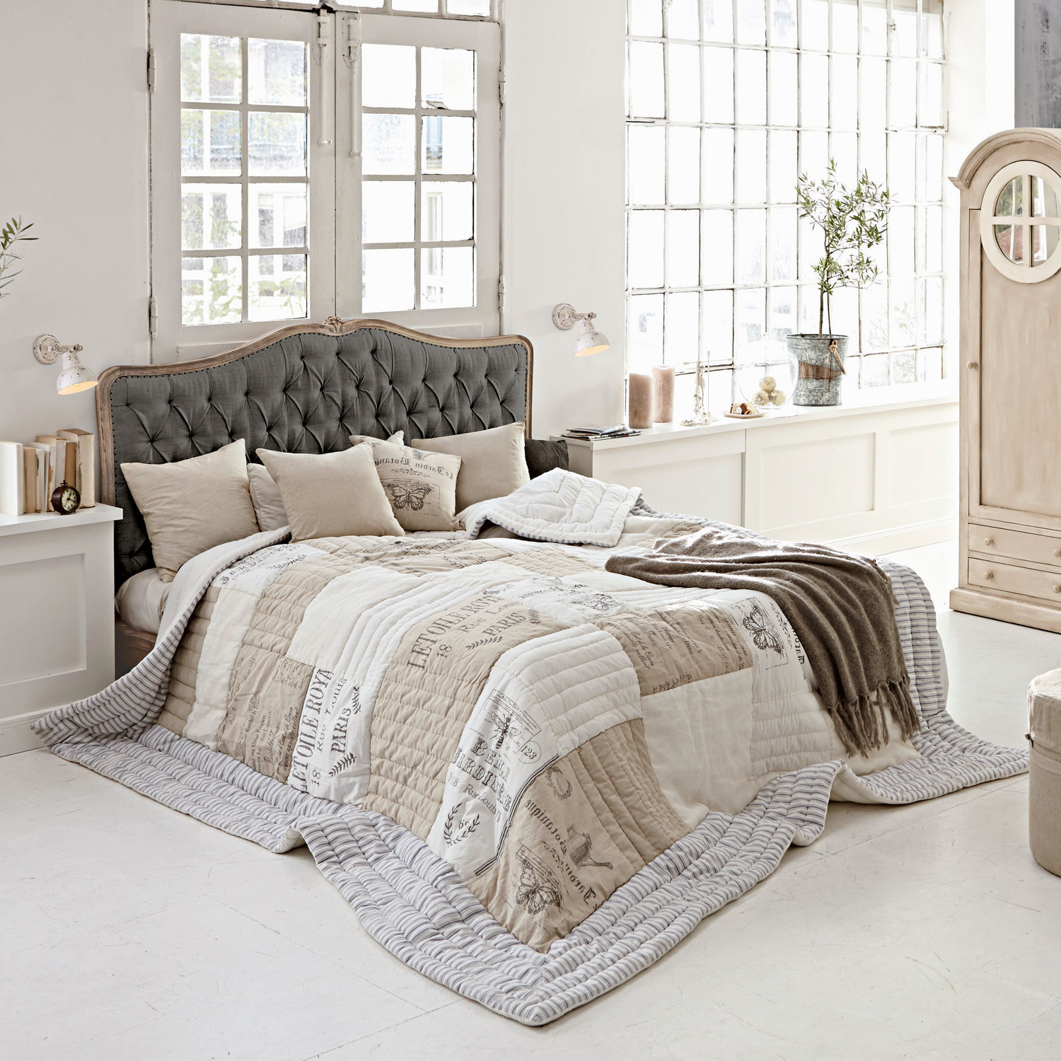 Bett Declaire Gemütliches Schlafzimmer mit Bett und grauem, gepolstertem Kopfteil sowie beige-weißer Vintage-Steppdecke