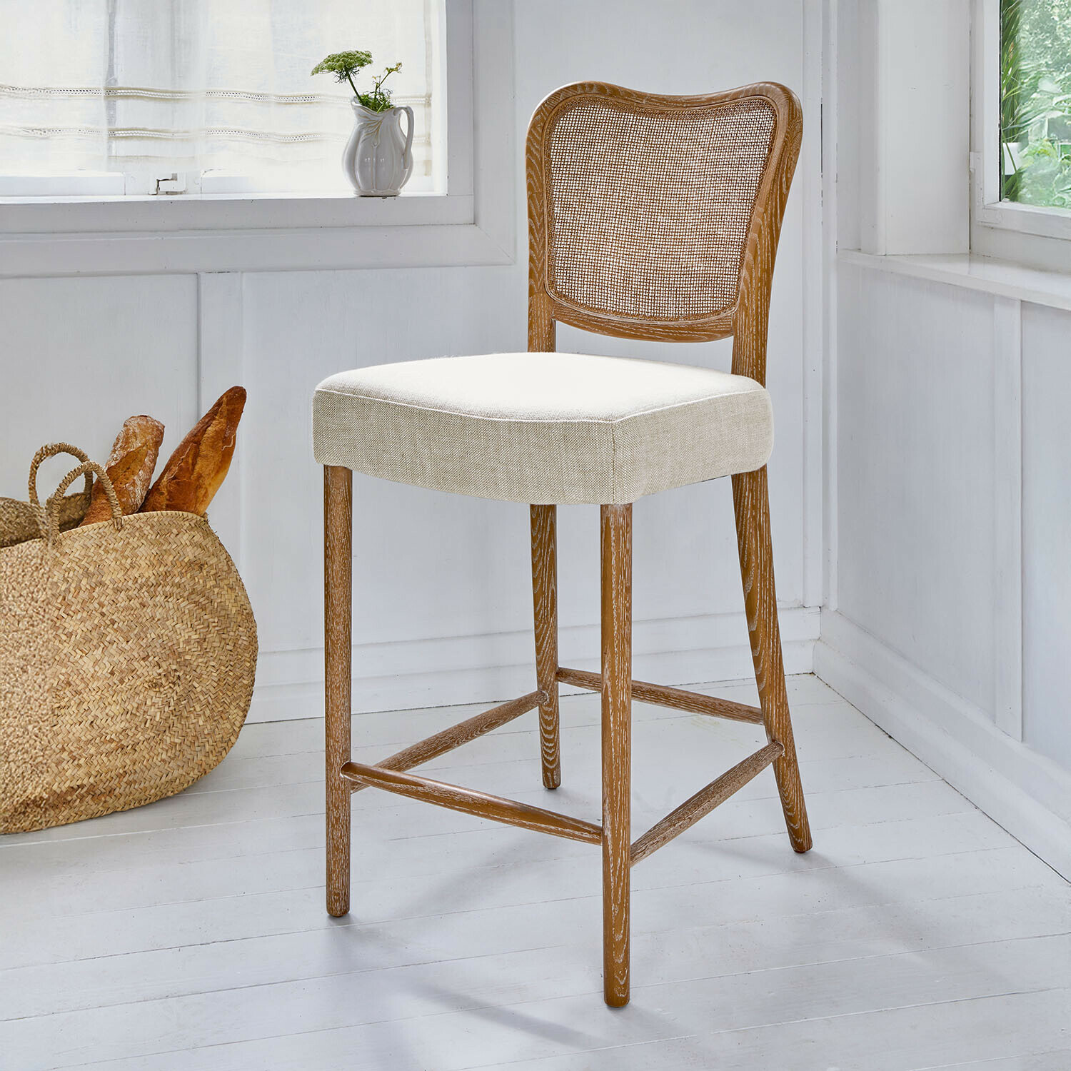 Barhocker mit hellem Leinenpolster und naturfarbenem Holzrücken mit Geflecht im modernen Landhausstil