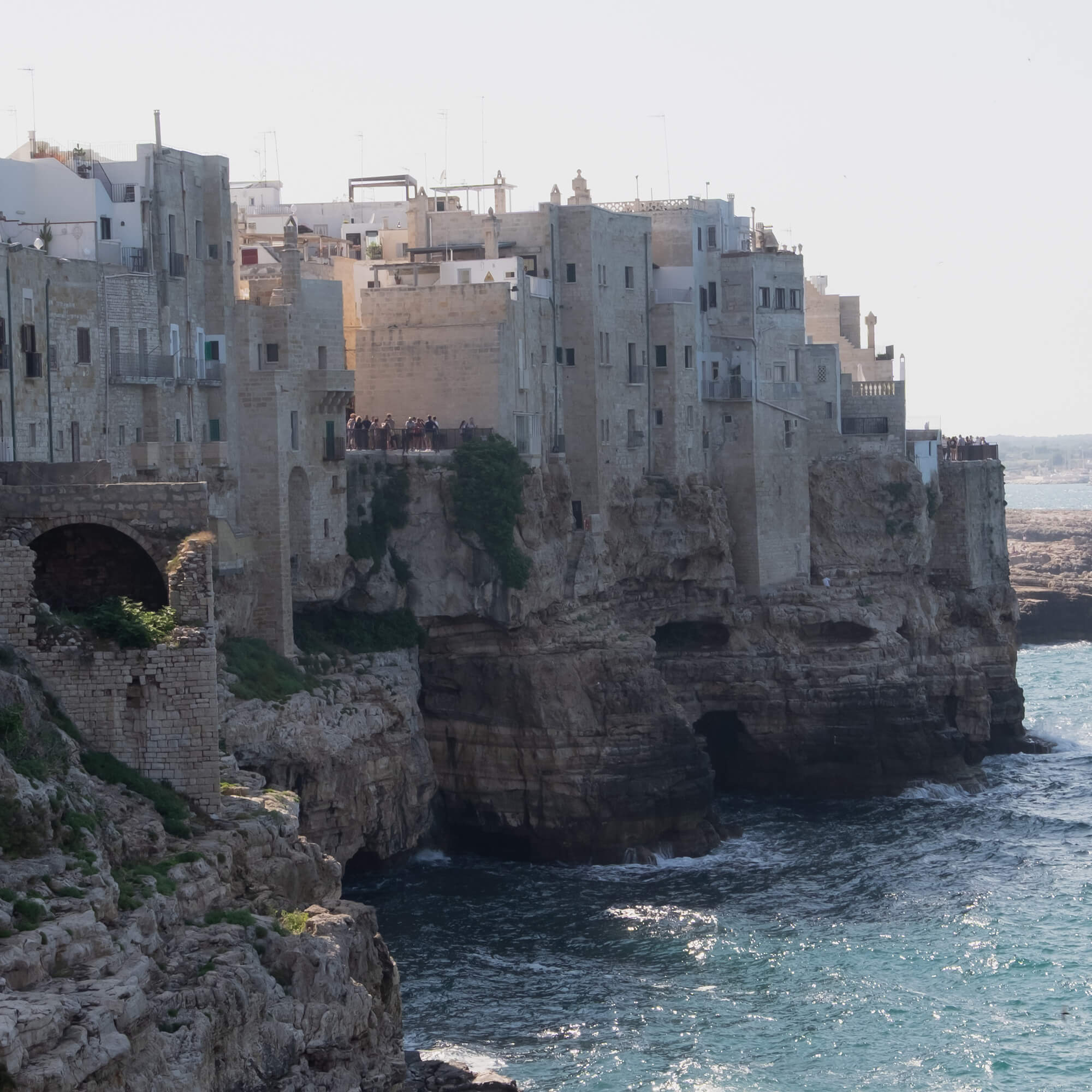 Alte steinerne Gebäude auf Klippe über dem Meer mit türkisfarbenem Wasser und Felsen darunter