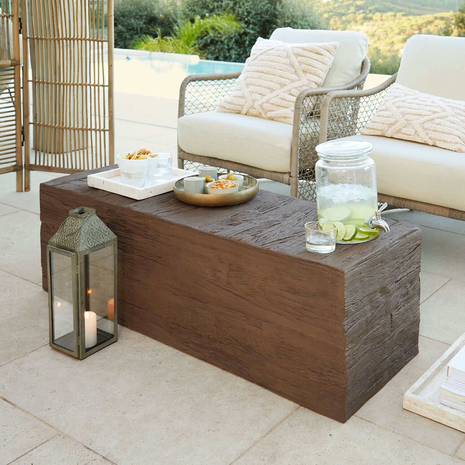 Couchtisch Fenwarden Brauner Couchtisch mit Holzstruktur auf Terrasse mit cremefarbenen Kissen und Zitronenlimonade