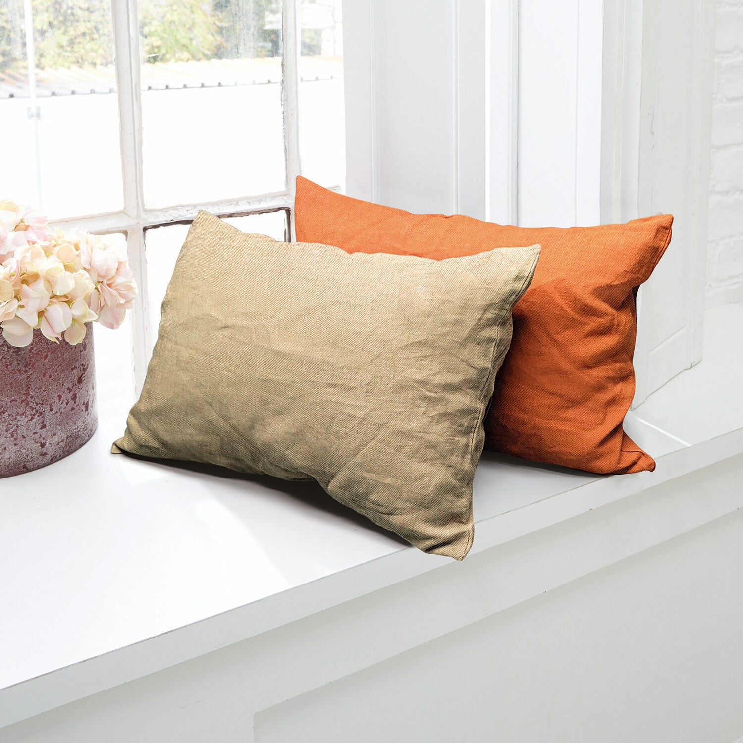 Kissenhülle 2er Set Balesta Zwei dekorative Kissen aus Stoff in Beige und Orange auf weißem Fensterbrett