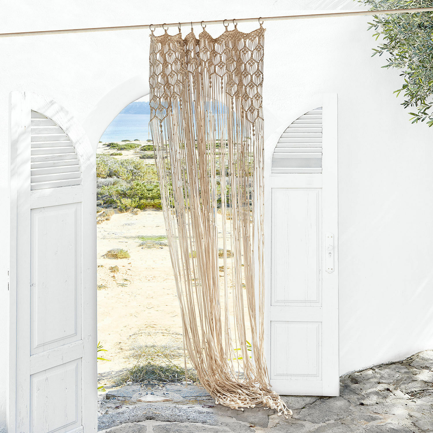 Gardine Manville Beige Baumwoll-Makramee an weißem offenem Tor mit Blick auf Strand und Meer