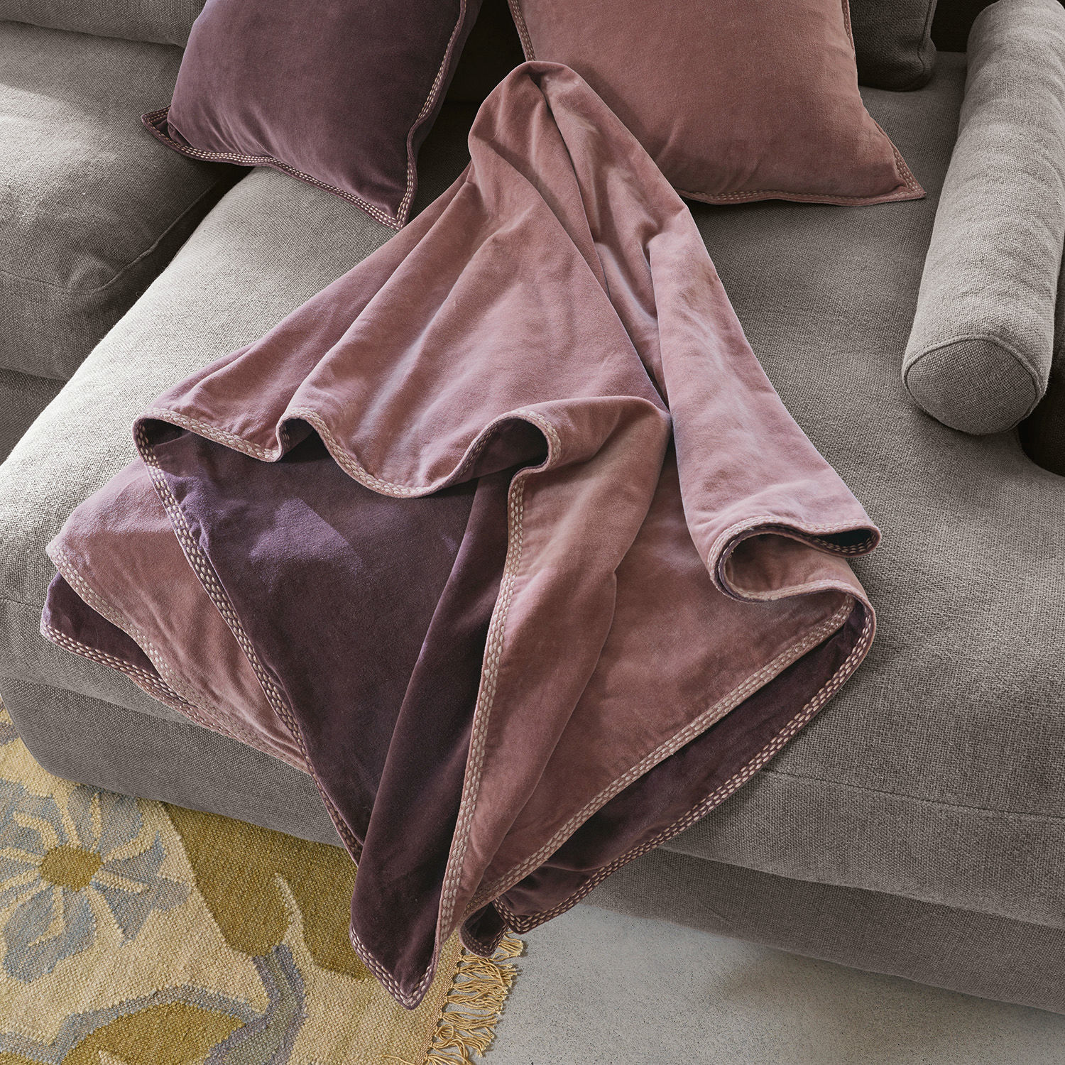 Plaid Murs Wendedecke aus weichem Samt in Rosa- und Violetttönen auf grauem Sofa, dekorativer Wohntextil