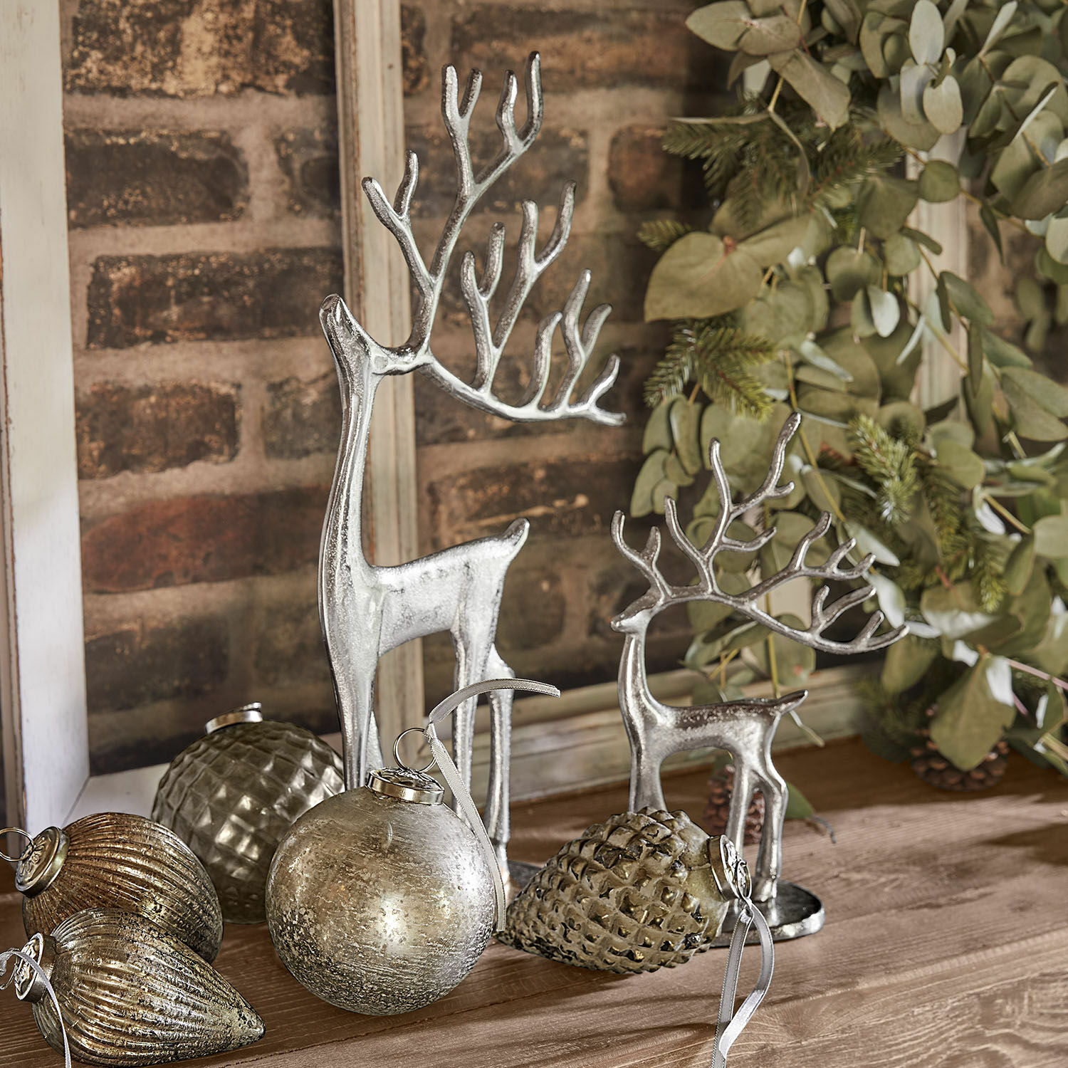 Deko-Rentier 2er Set Zerlay Silberne Rentierfiguren und Weihnachtsdekorationen auf Holztisch mit grünen Zweigen arrangiert
