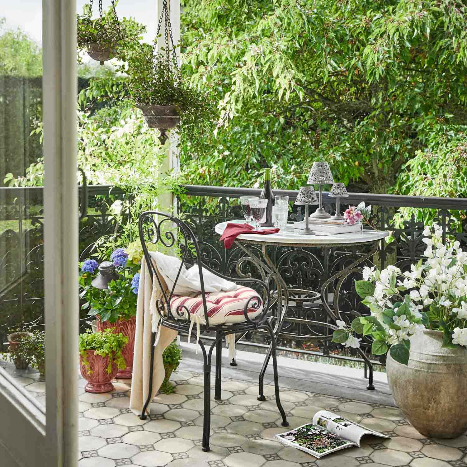Balkon mit Metalltisch und Stuhl, dekorative Pflanzen in Töpfen, gemütliche Outdoor-Atmosphäre