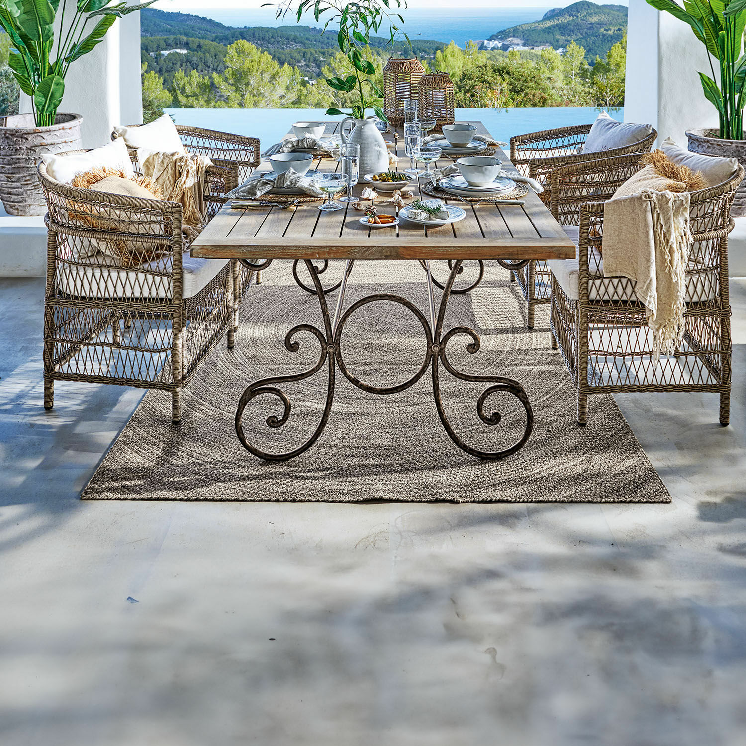 In- & Outdoorteppich Plimmerton Gartenmöbel-Set aus Rattan und Holz mit Dekoration auf Terrasse mit Meerblick