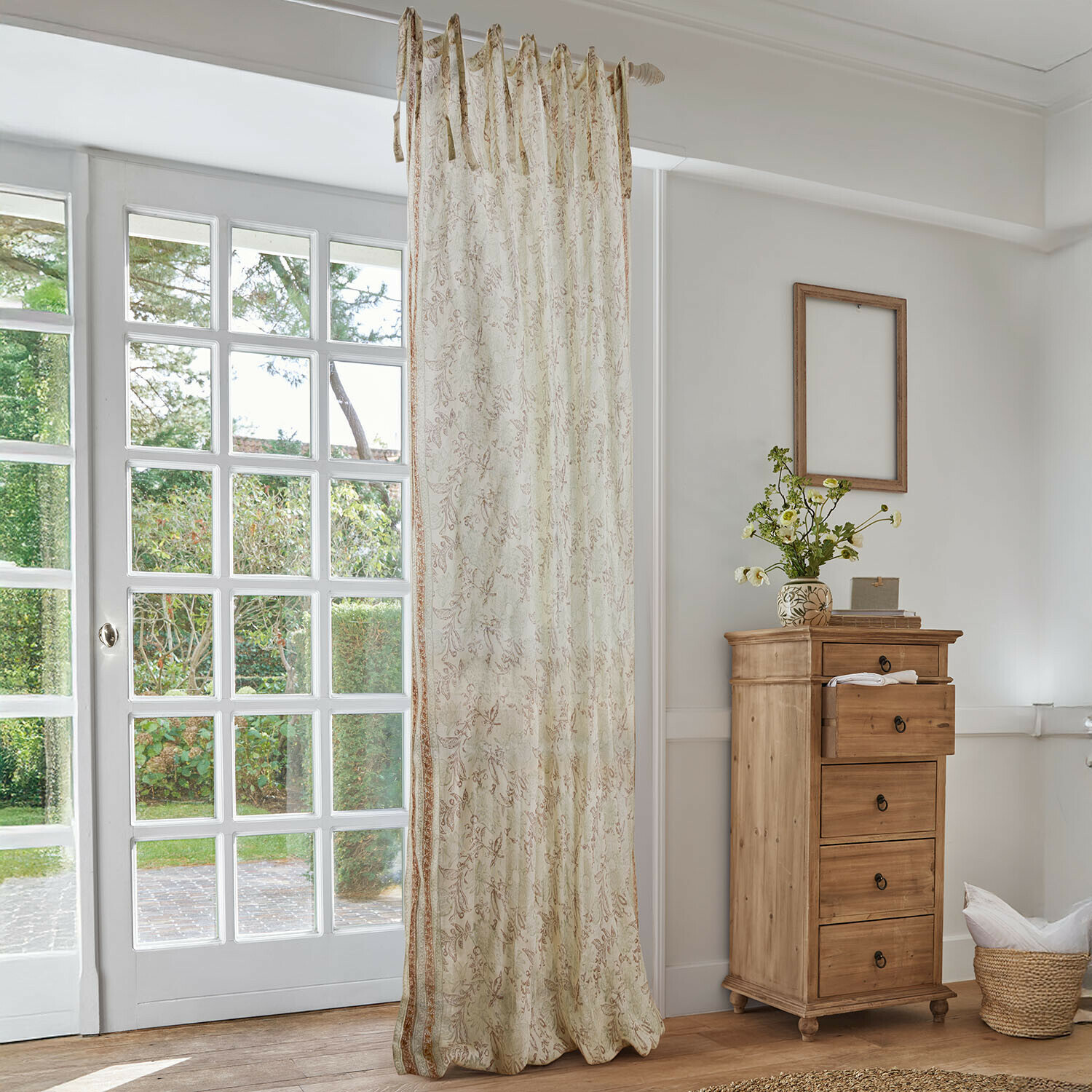 Gardine Floréane Beiger Vorhang mit zartem Blumenmuster in hellem Wohnzimmer mit Holzkommode und großem Fenster