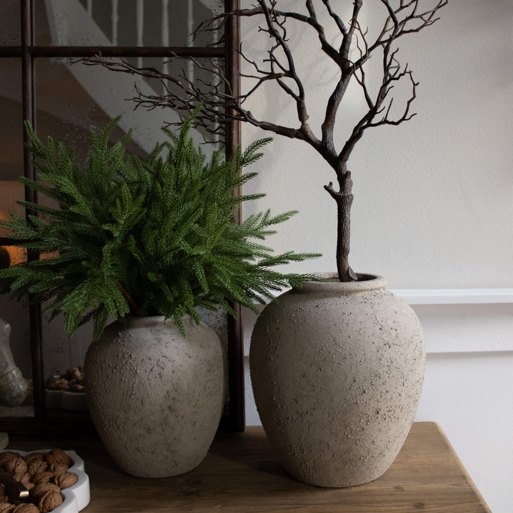 Zwei dekorative graue Steinvase auf Holztisch mit grünen und trockenen Zweigen