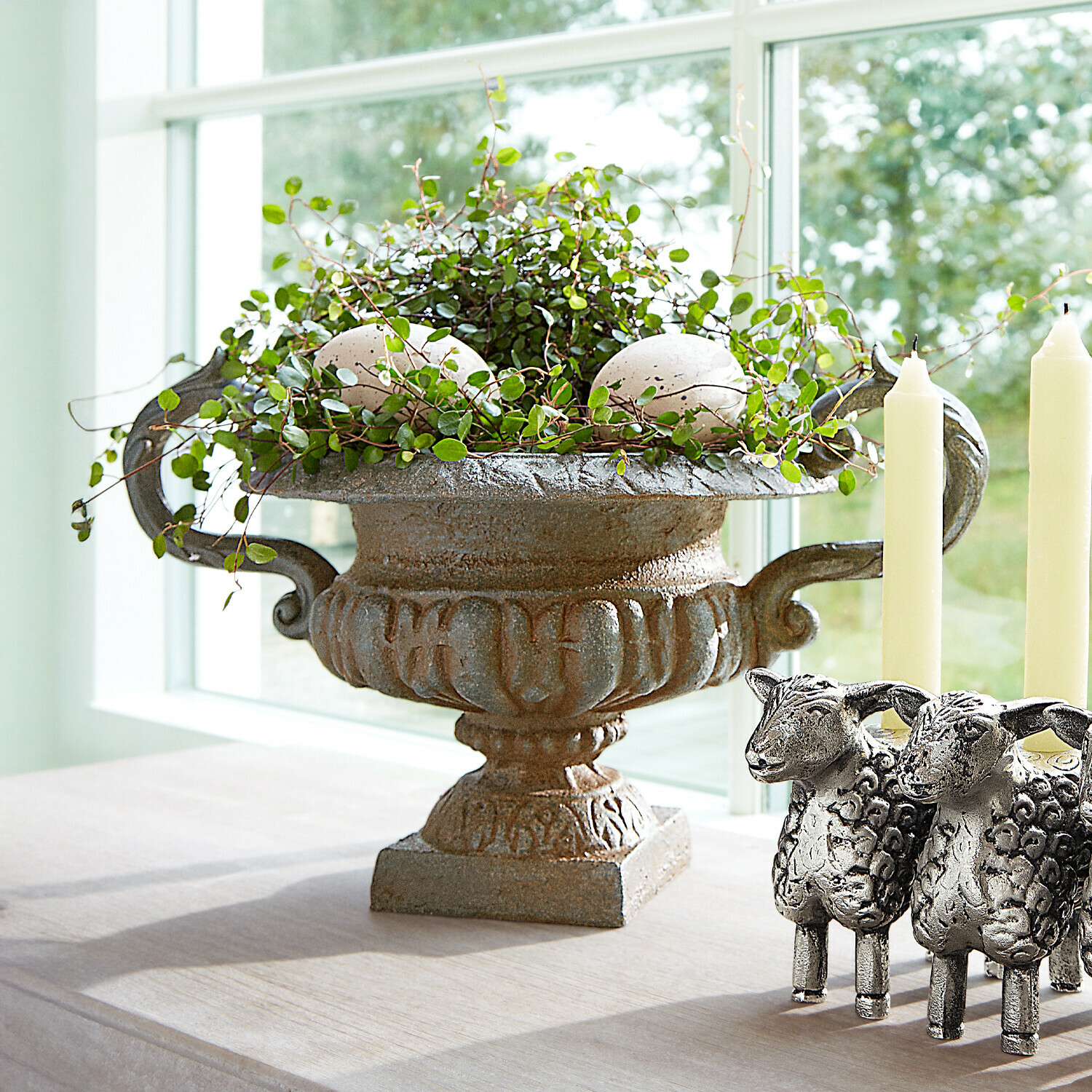 Dekorative Vintage-Metallschale mit grünen Blättern und weißen Steinen auf Tisch