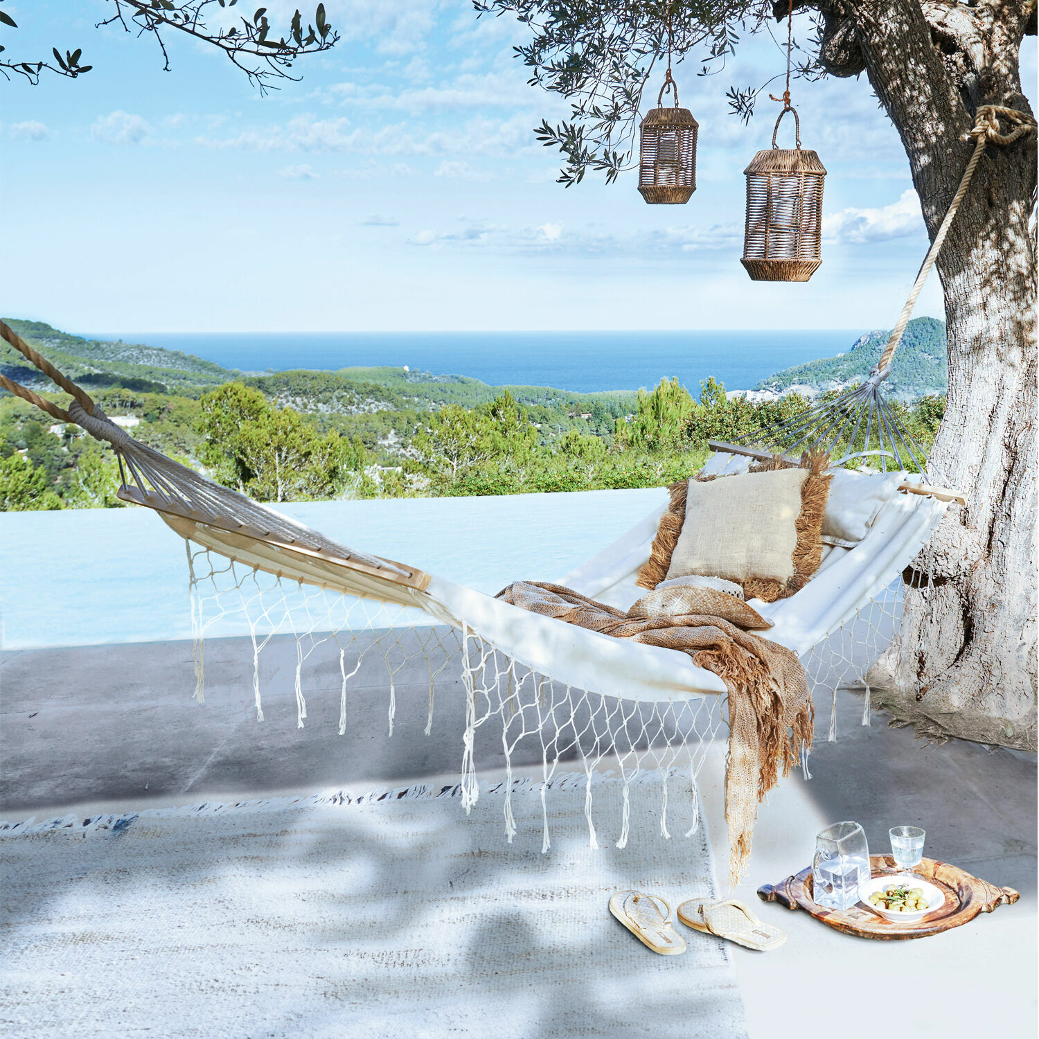 Weißer Baumwoll-Hängematte mit Kissen und Decke auf Terrasse mit Meer- und Waldblick