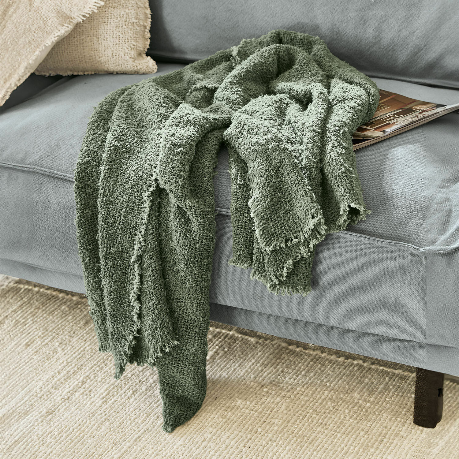 Plaid Juliana Weiche grüne Baumwolldecke auf grauem Sofa, dekorativer und gemütlicher Wohnaccessoire