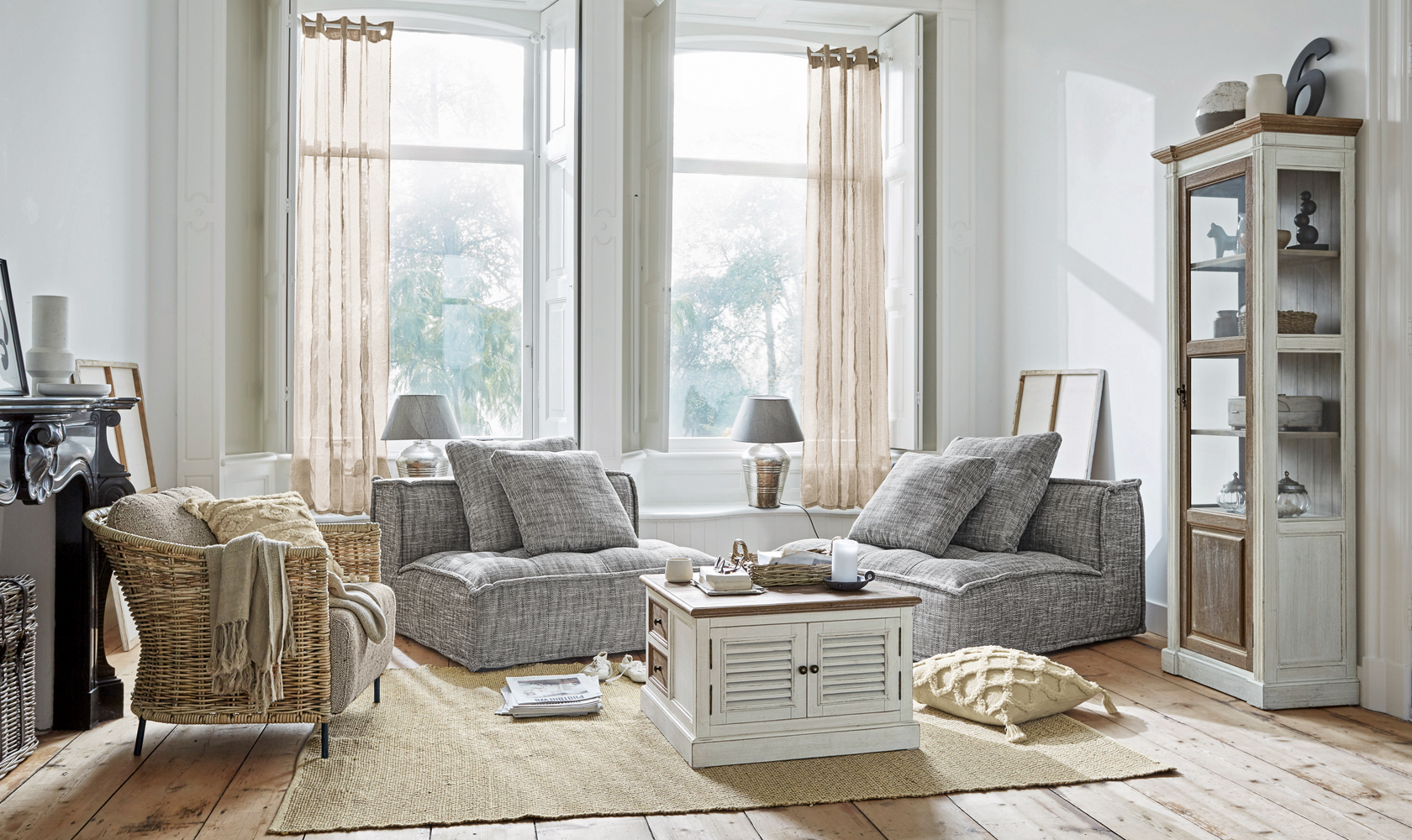 Helles Wohnzimmer mit grauen Sesseln und weißem Holzschrank auf Juteteppich, moderner skandinavischer Stil
