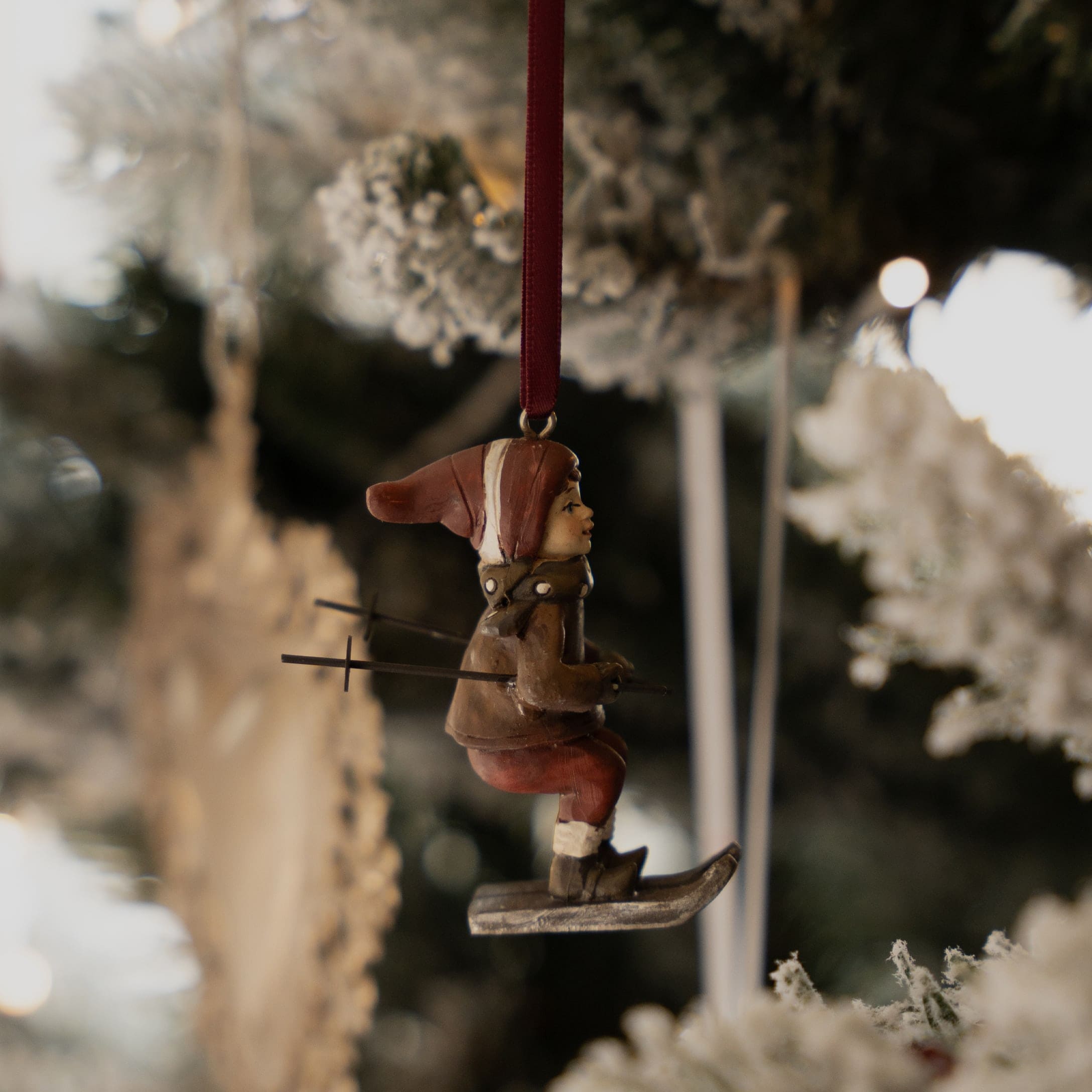 Weihnachtsschmuck mit Skifahrer-Figur in brauner Kleidung und roter Mütze am Weihnachtsbaum