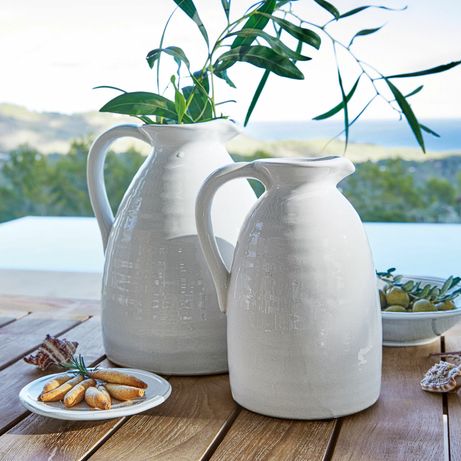Vase 2er Set Yarick Weiße Keramik-Krüge auf Holztisch mit grünen Blättern und Snacks, Tischdekoration